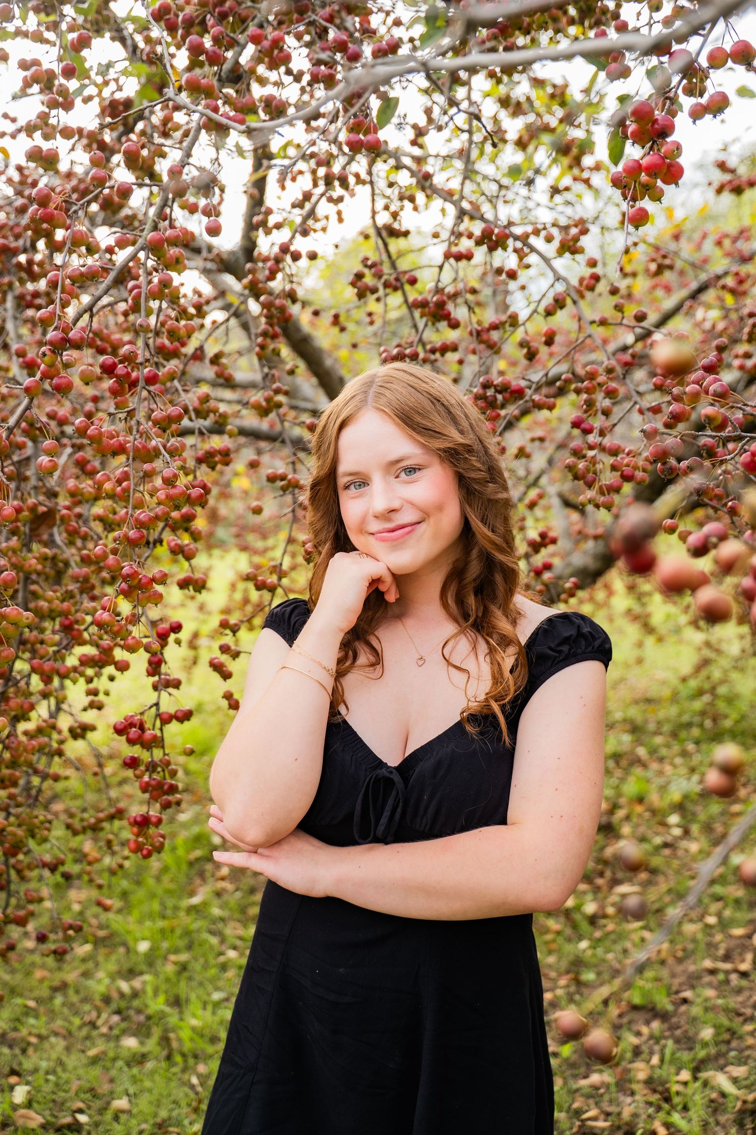 Senior portrait session in autumn orchard with red crabapple trees and natural lighting.