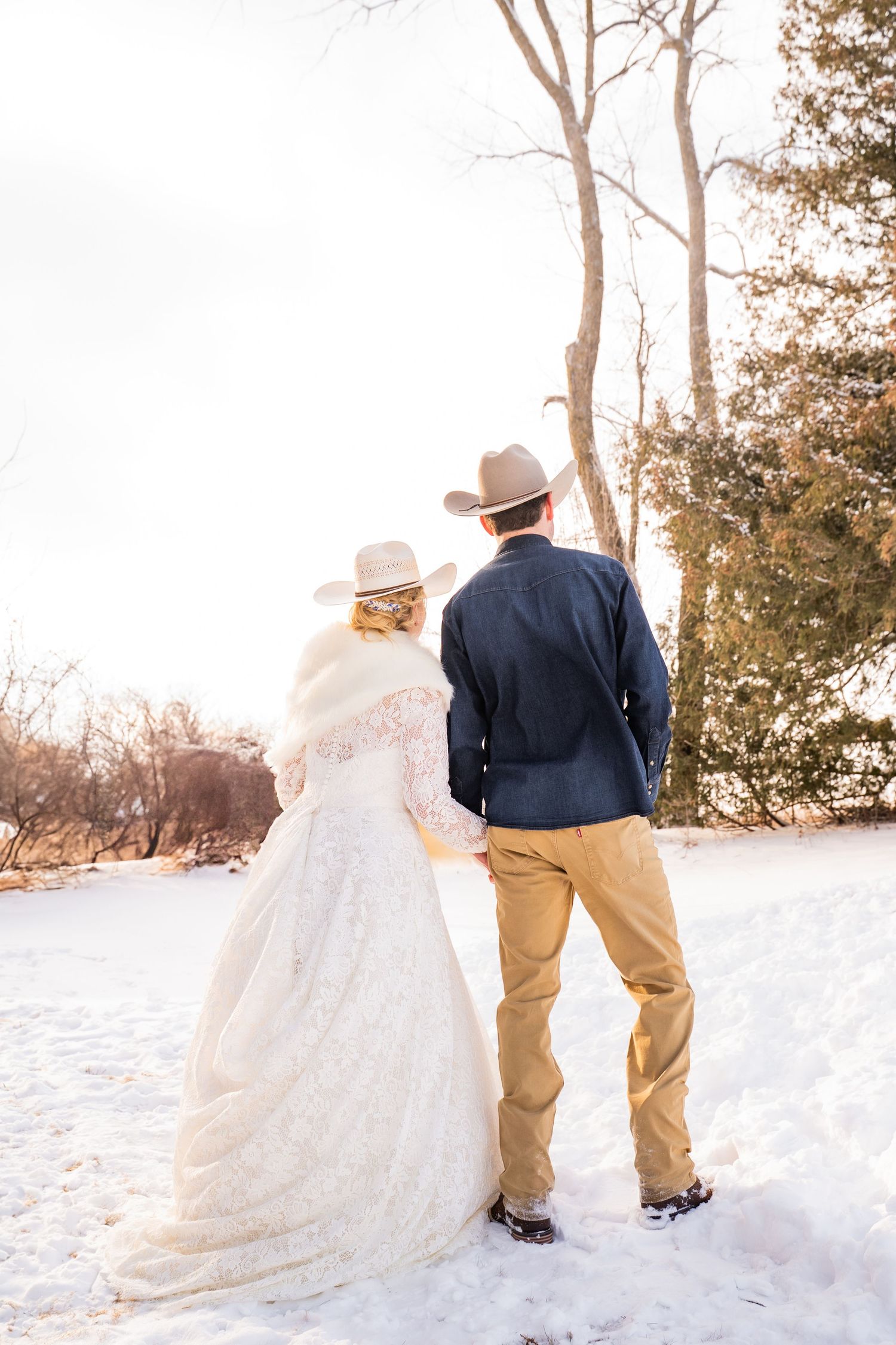 Winter wedding portrait showing couple walking through snow-covered landscape.