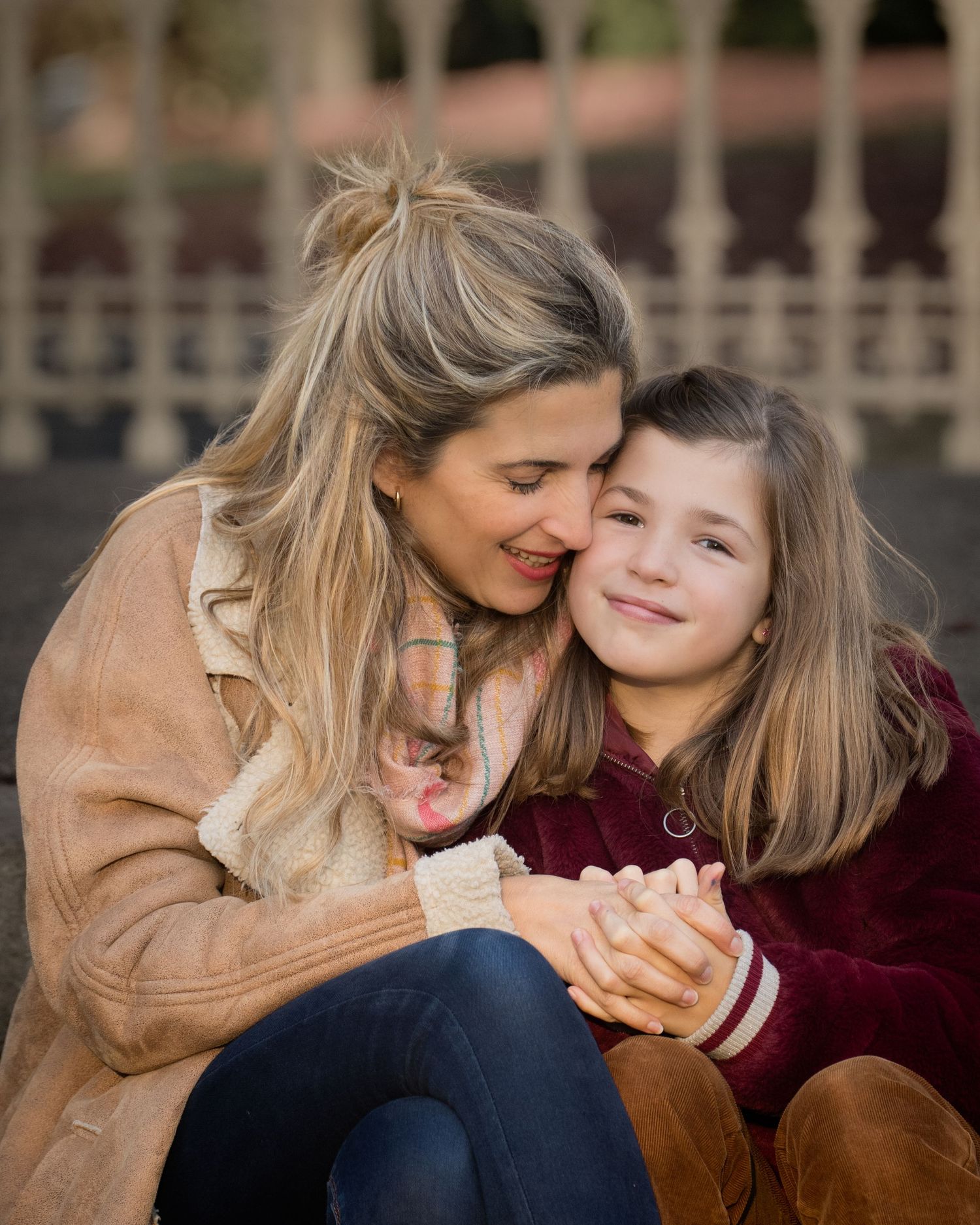 Family photograph. Tender moment between parent and child sharing an embrace outdoors.