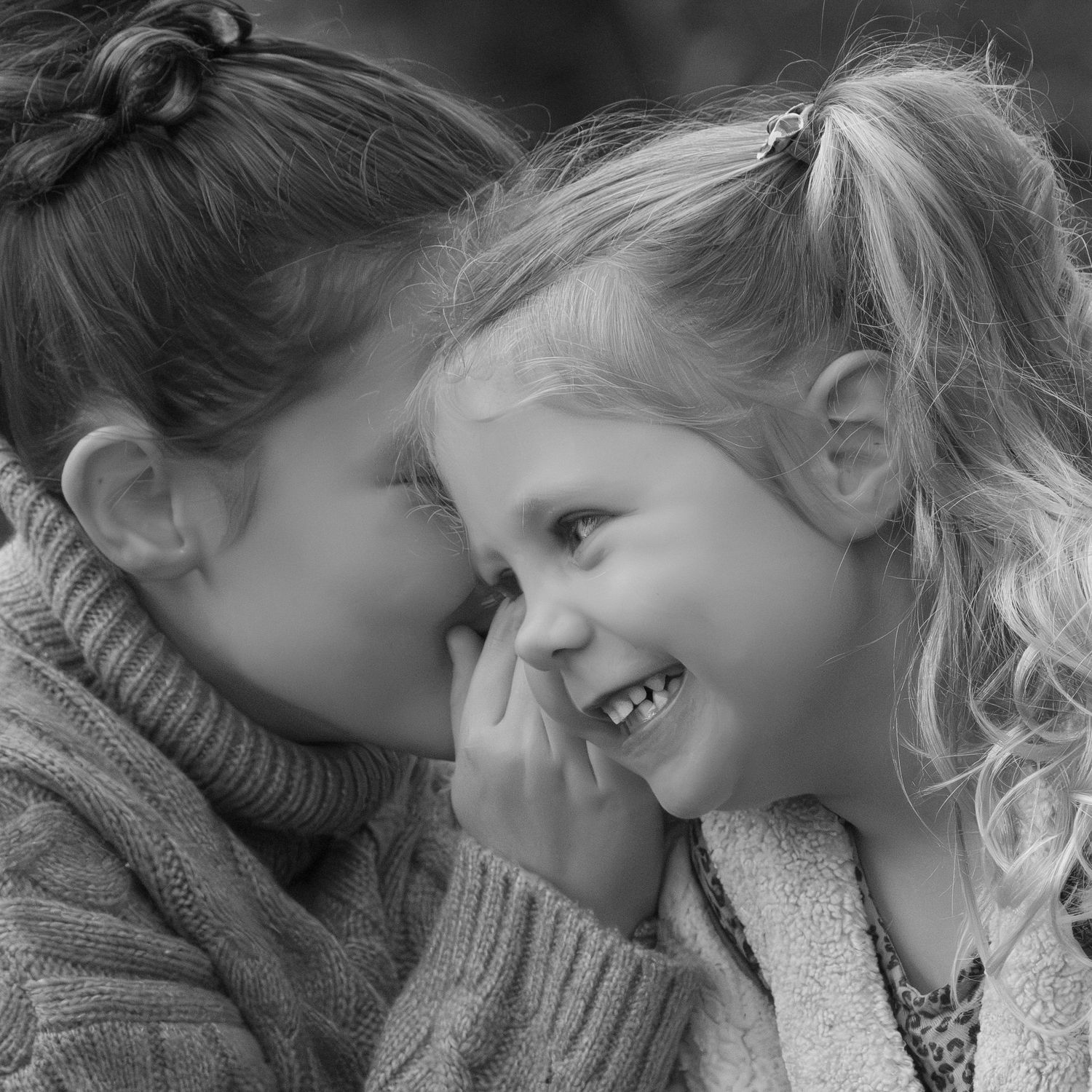 Close-up black and white portrait of children sharing intimate moment.
