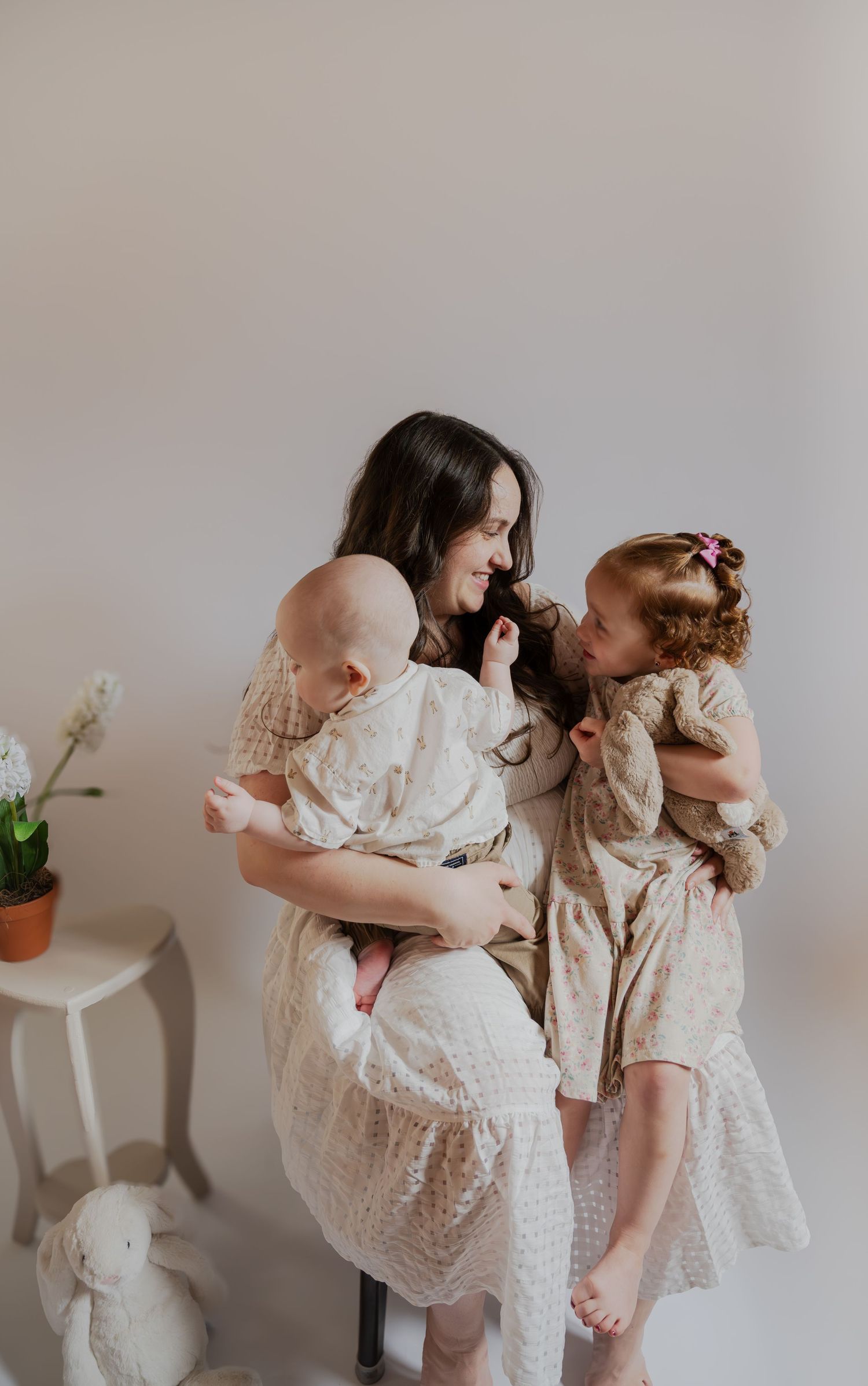 People in cream colored dresses sharing a sweet moment together in a light minimalist setting.