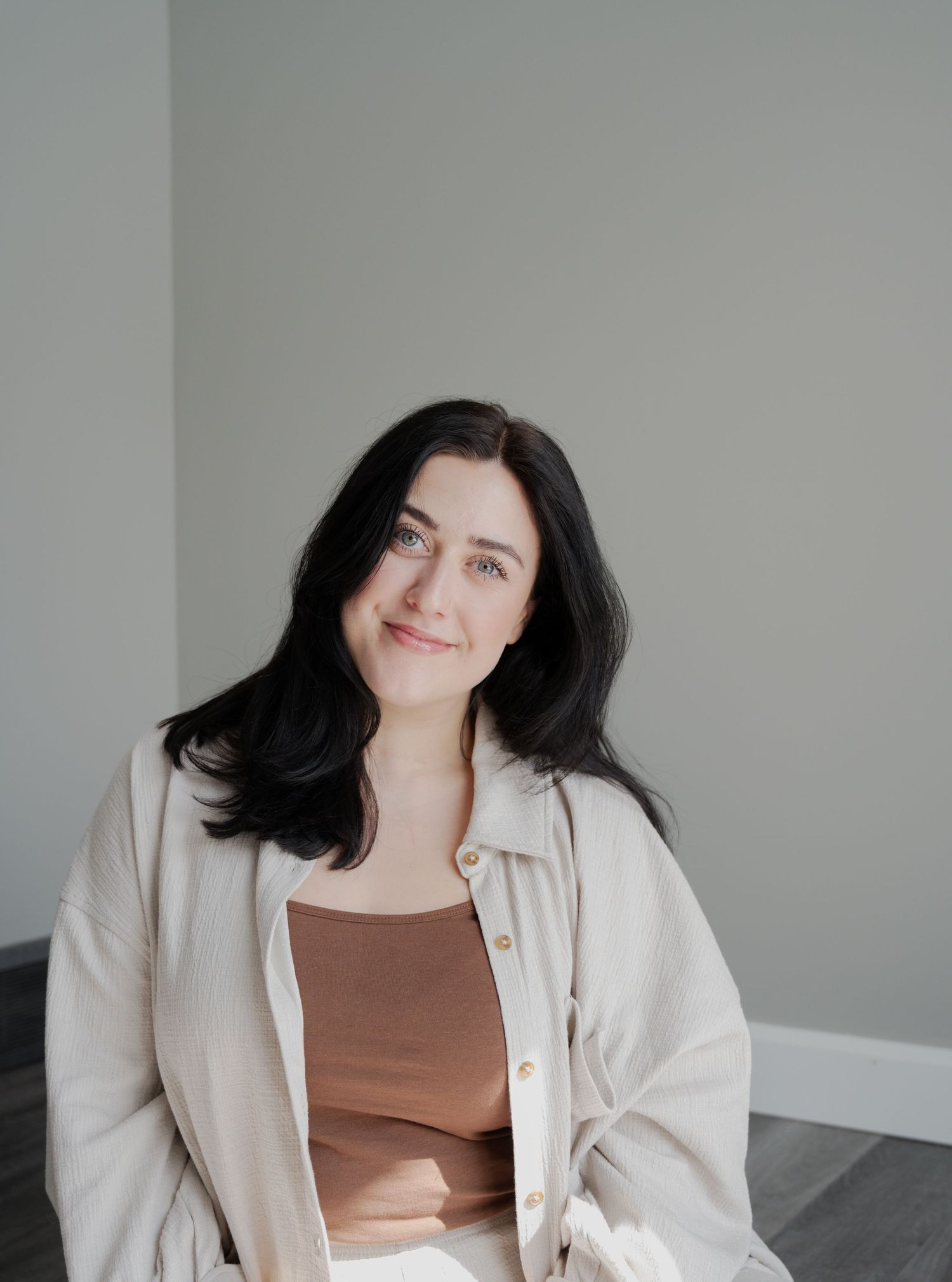 Portrait of someone in casual layers against neutral background with soft lighting.