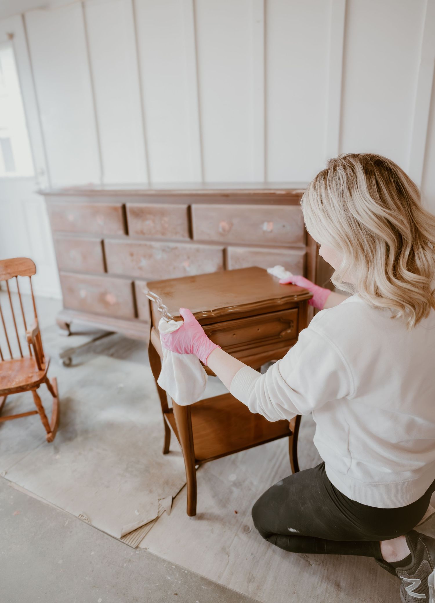 Person in white shirt examining wooden furniture piece in rustic setting.