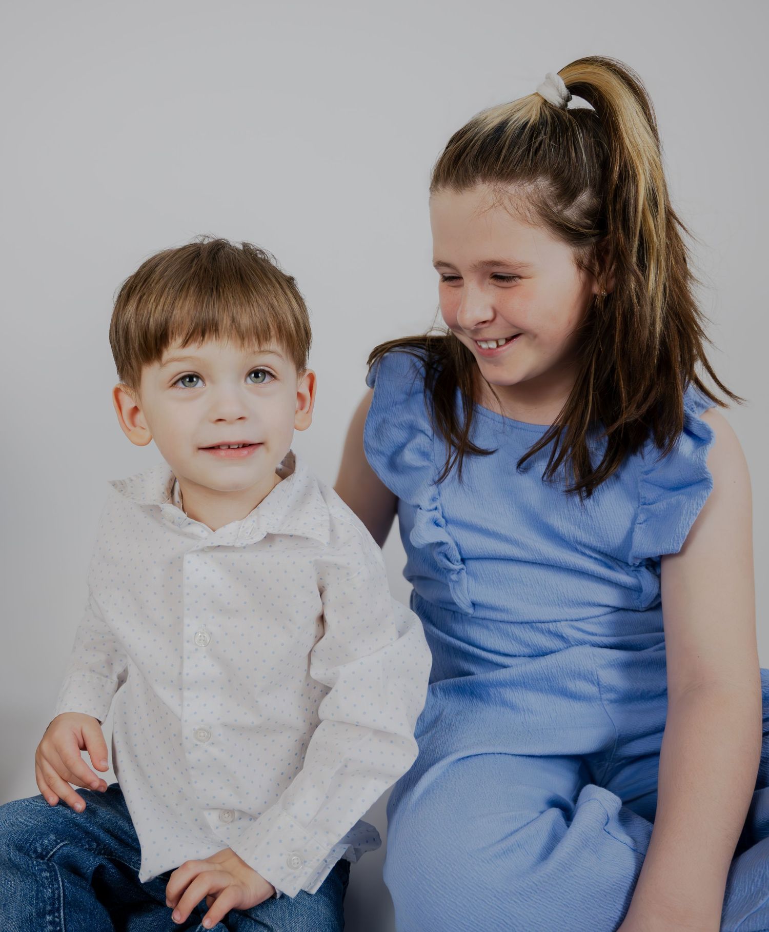 Casual portrait of two people in blue and white clothing against neutral background.