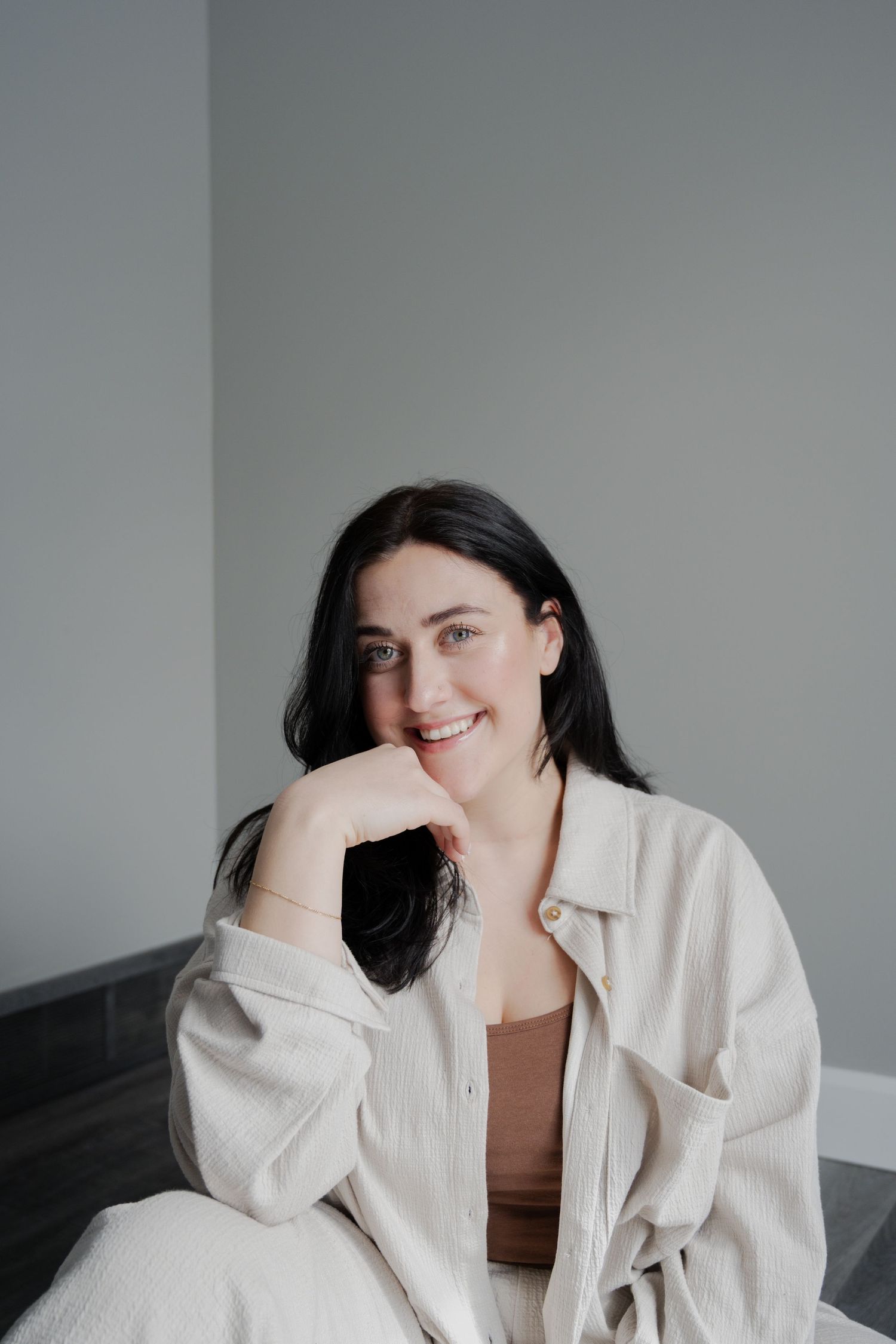 Casual indoor portrait of woman in beige jacket and brown top with relaxed pose.