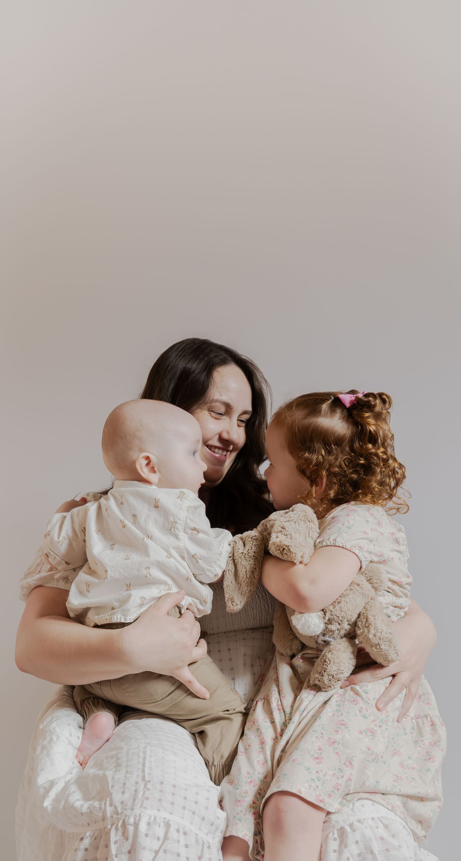 A heartwarming family moment captured against a neutral backdrop with vintage-style clothing.