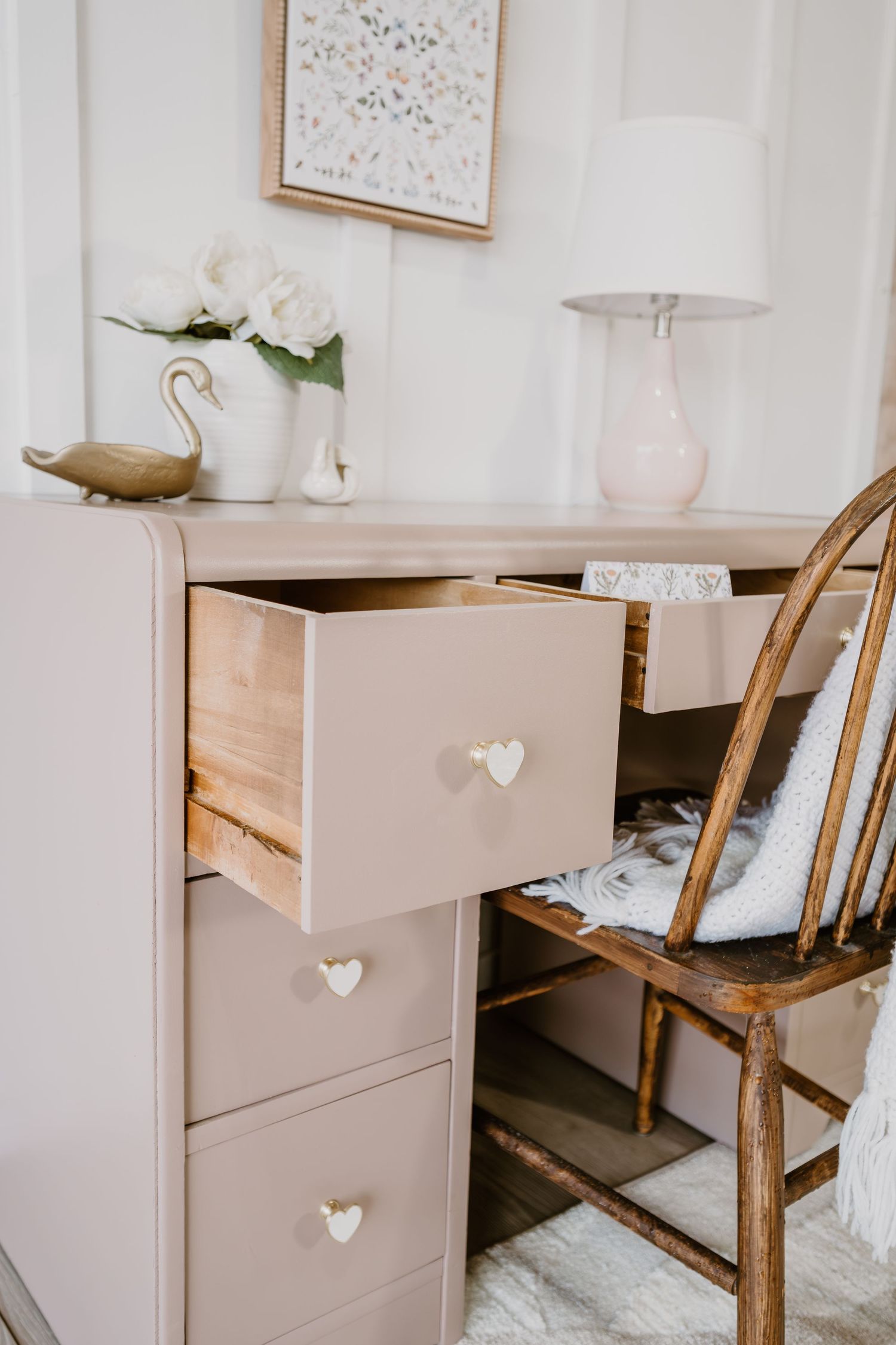 Beige desk with heart-shaped knobs and wooden chair in minimalist room setting.