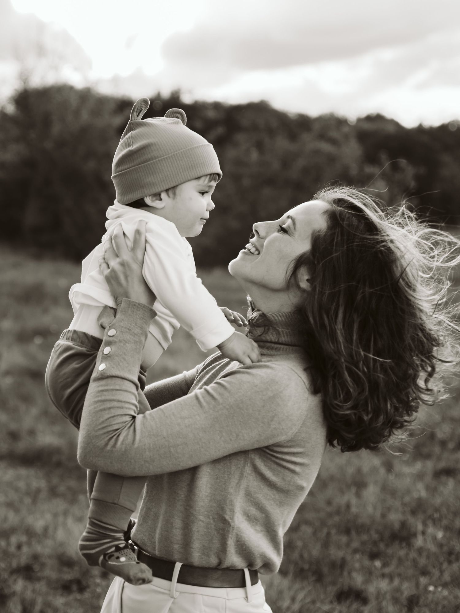 Black and white portrait of mother gazing lovingly at baby outdoors.