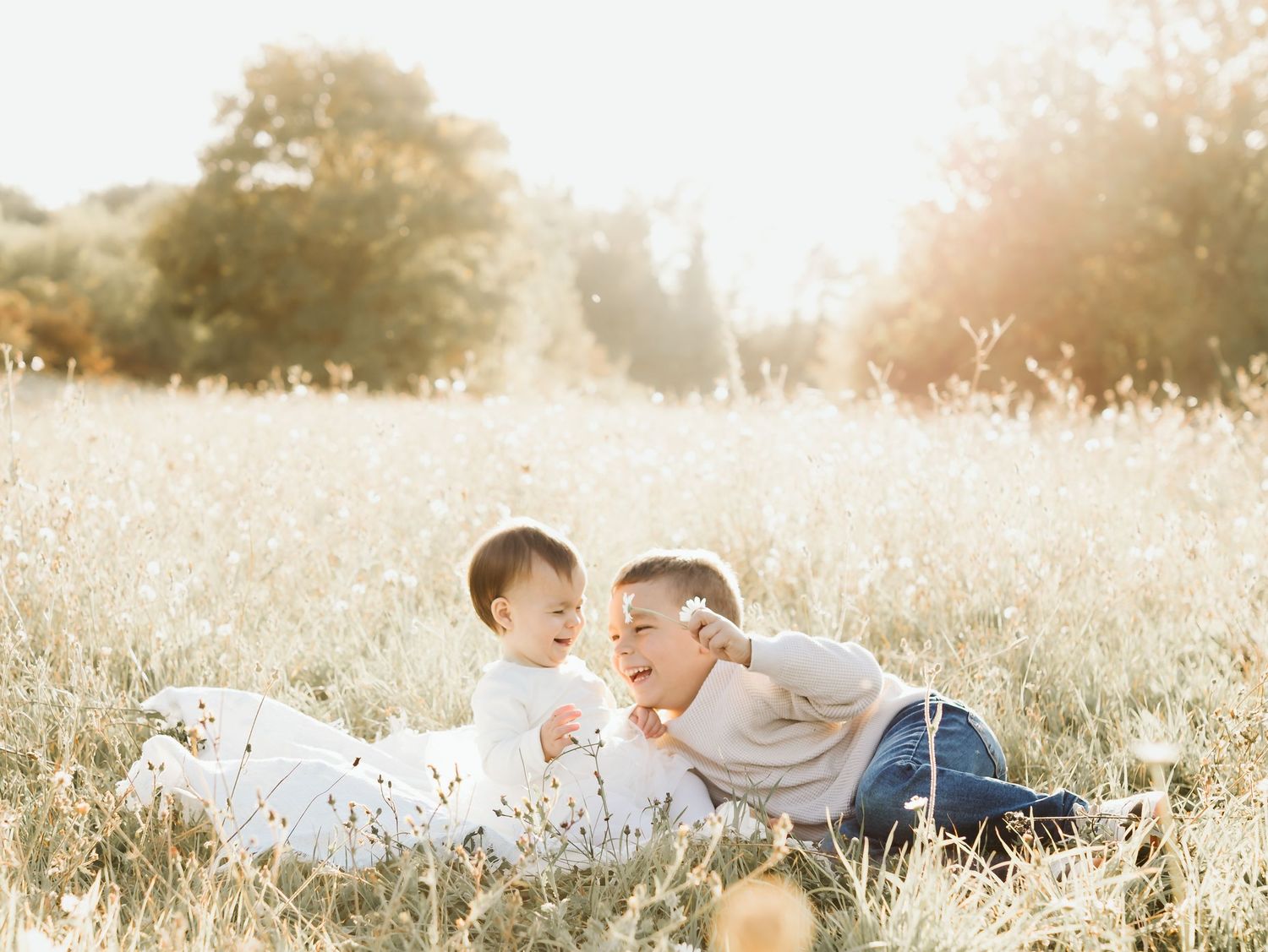 Mother and young child sharing a sweet moment lying together in a sun-drenched wildflower meadow.