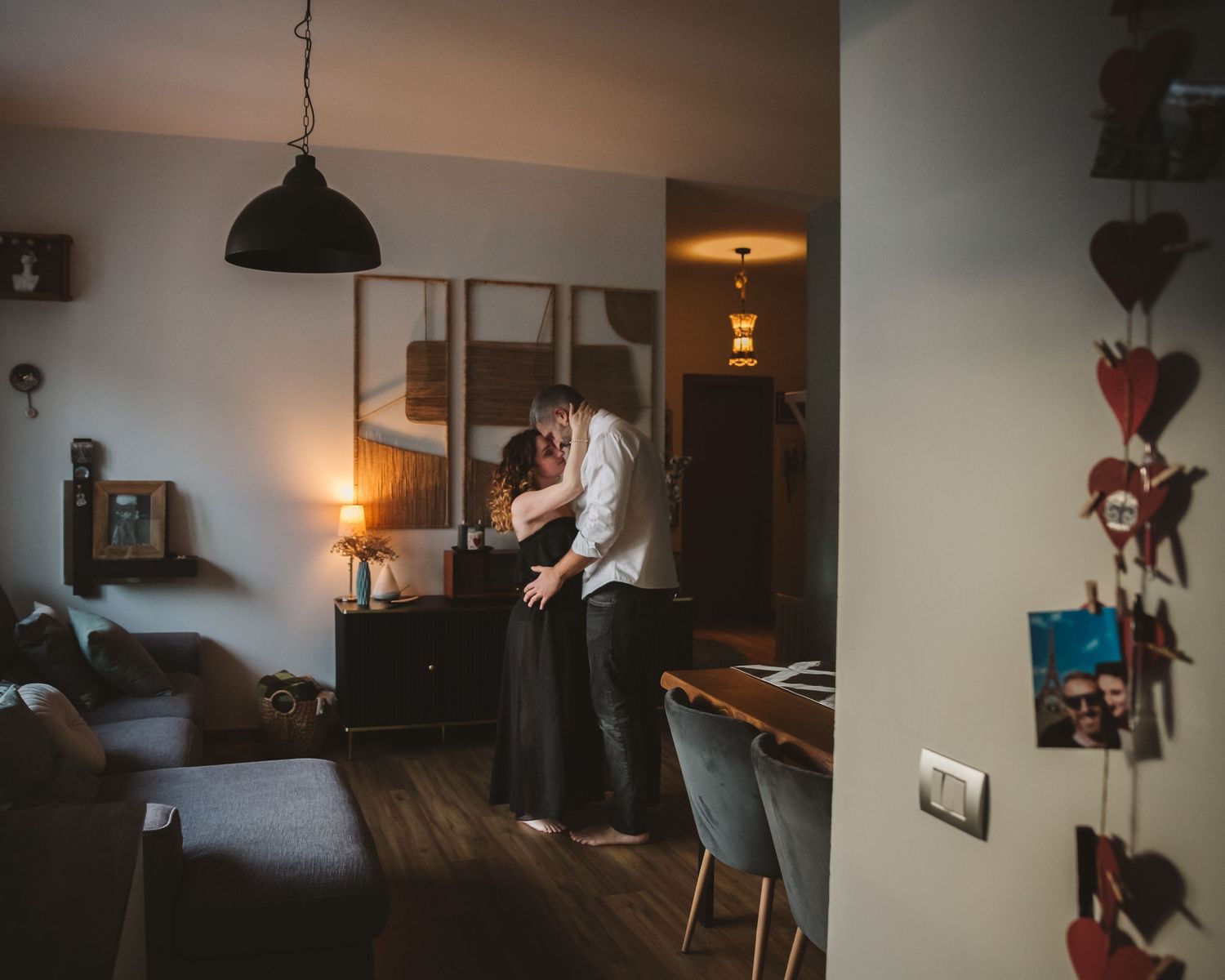 Couple sharing an intimate embrace in a warmly lit home interior with ambient evening lighting.