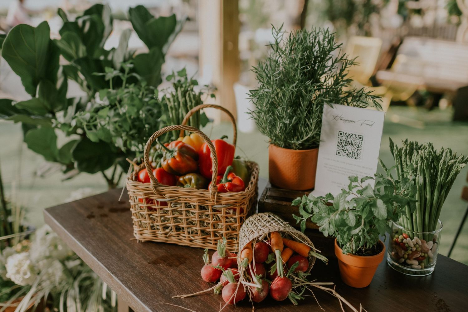 Fresh herbs and vegetables displayed with white flowers in rustic garden-themed setting.