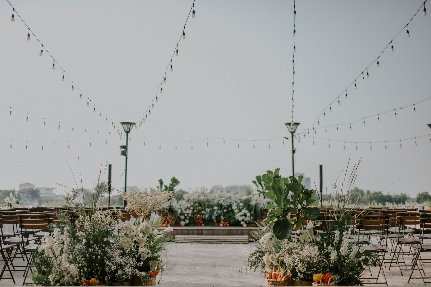 Wedding reception space decorated with string lights and greenery overlooking a serene lake.