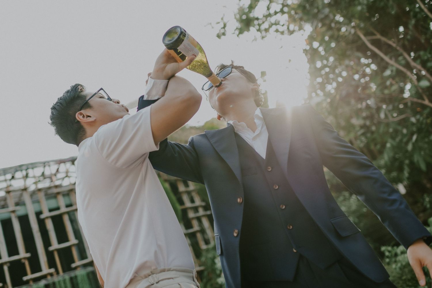 People drinking from bottles during an outdoor celebration with natural sunlight.