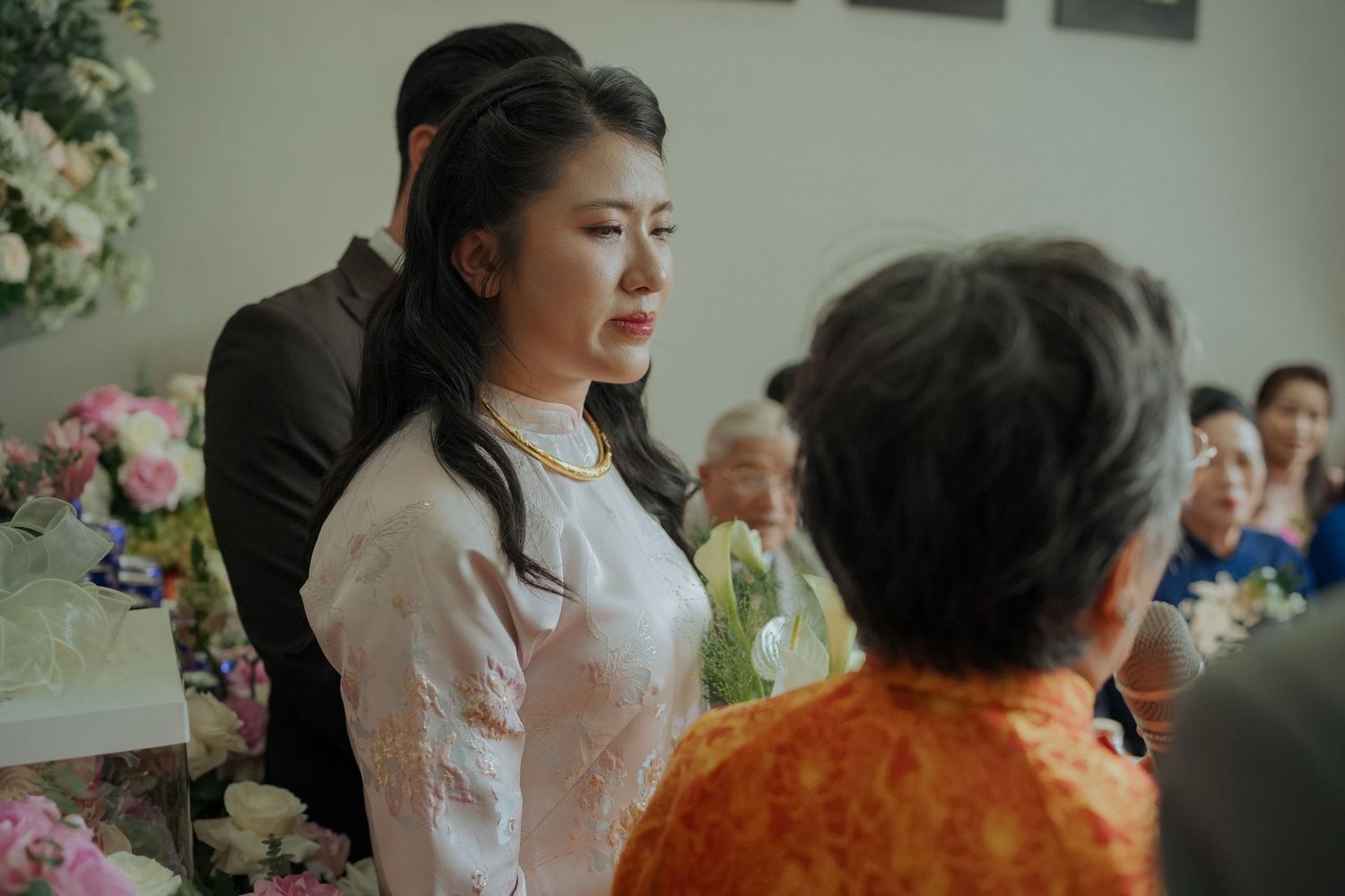 Traditional Vietnamese tea ceremony with guests gathered around decorated table.