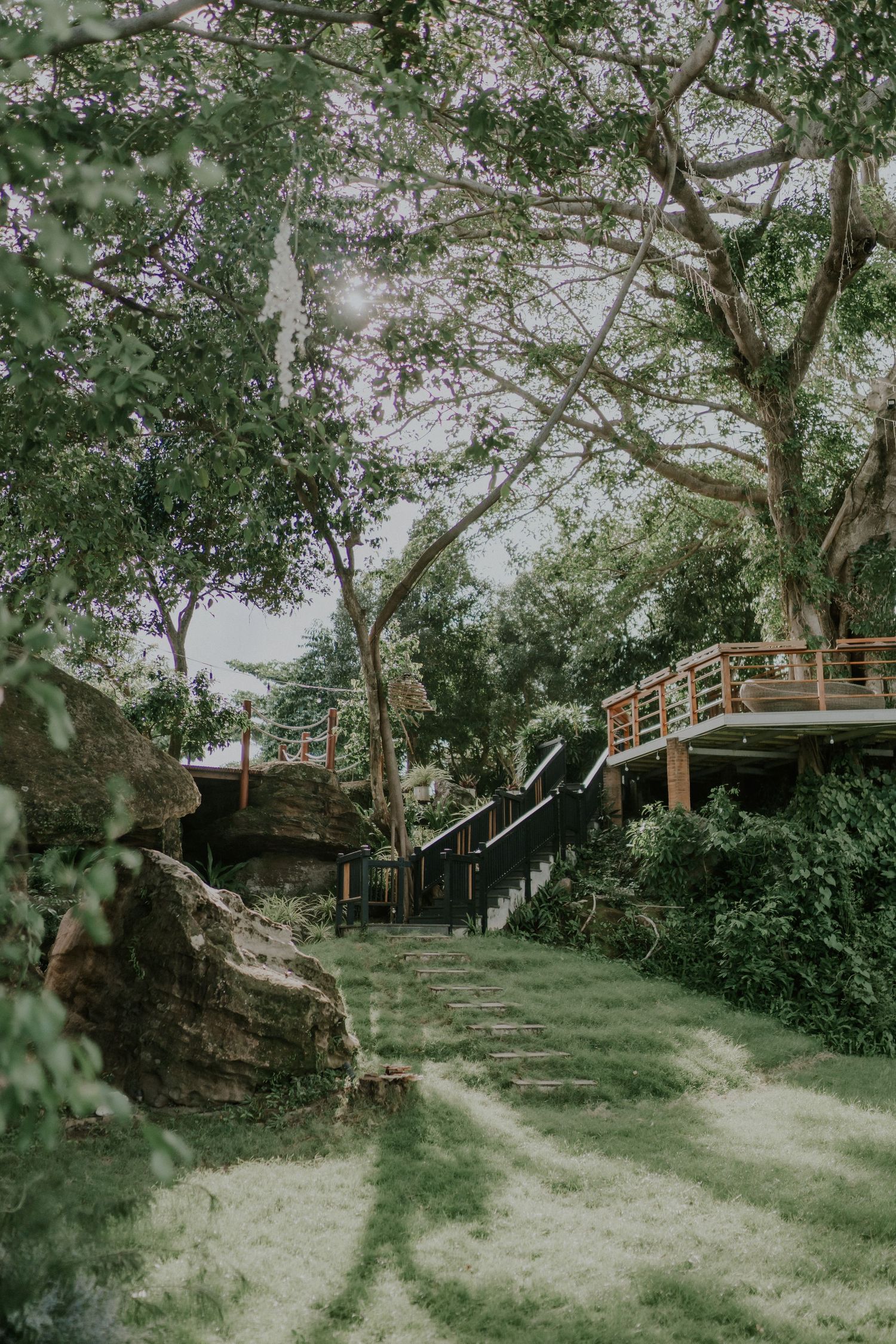 Scenic garden path with stone steps leading to elevated wooden deck among trees.