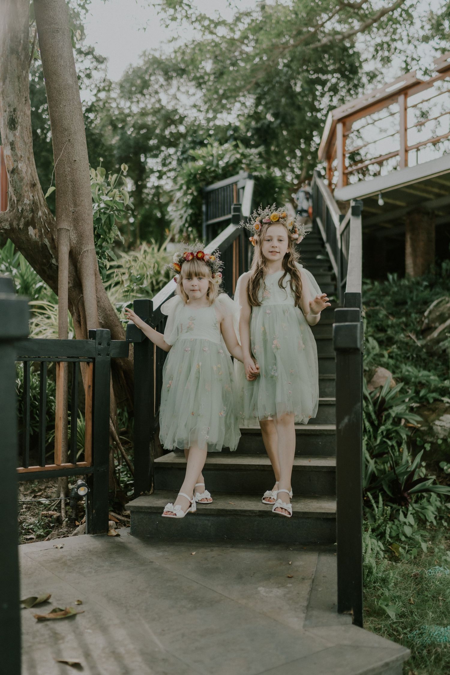 Two floral-dressed figures descending elegant garden stairs.