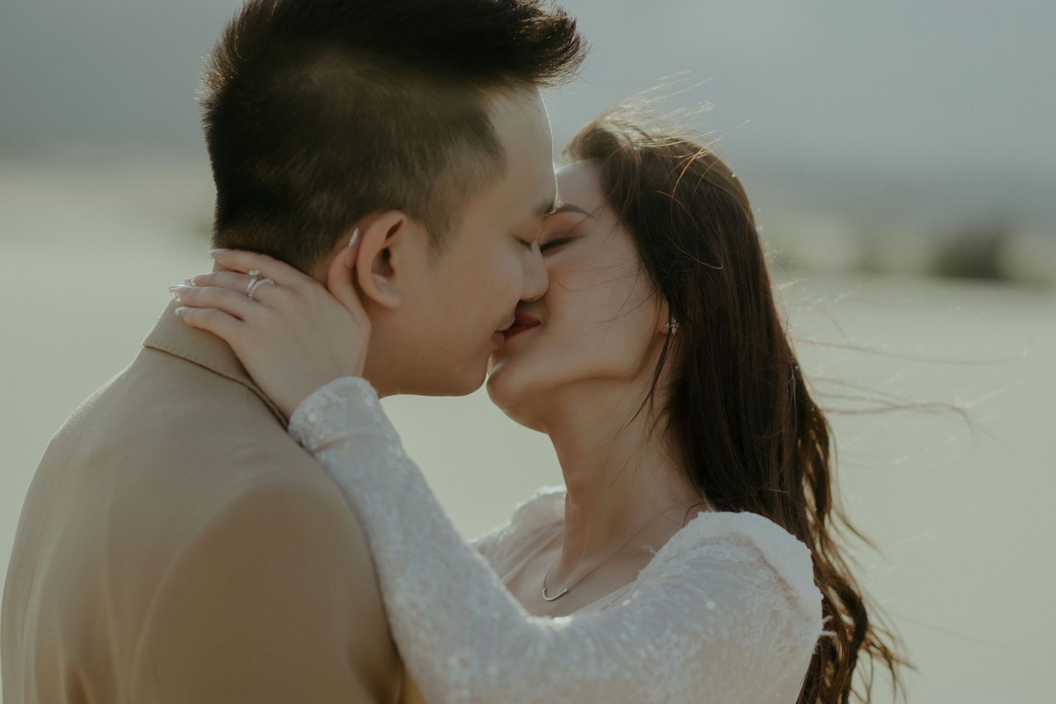 Intimate wedding couple shares a romantic kiss in warm desert lighting.