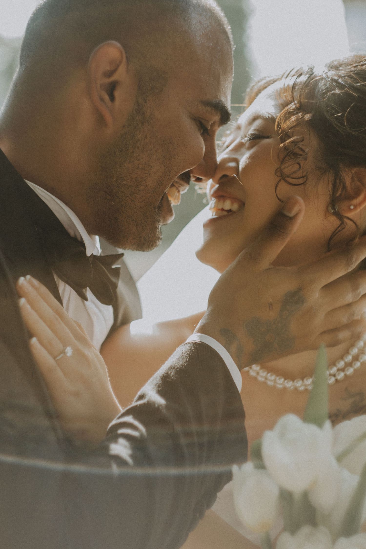An intimate wedding portrait capturing a joyful moment between newlyweds in warm sunlight.