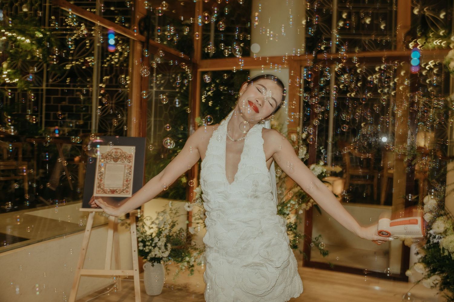 A joyful dancer in a white halter dress twirls on a dance floor decorated with twinkling lights and greenery.