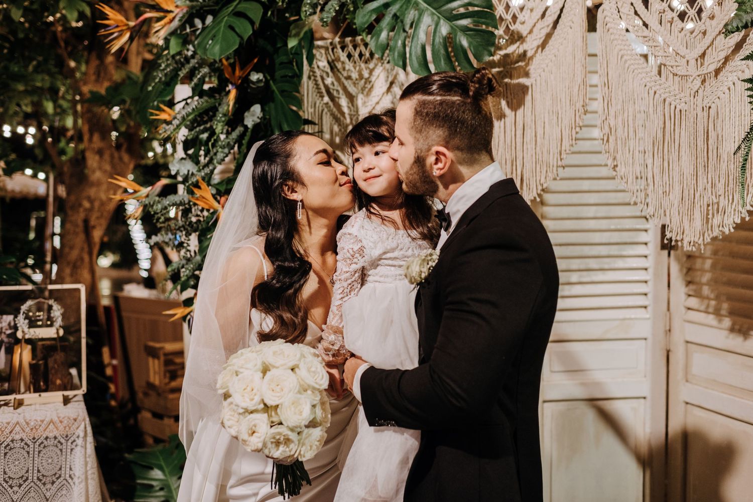 Intimate wedding moment under string lights and tropical decor.