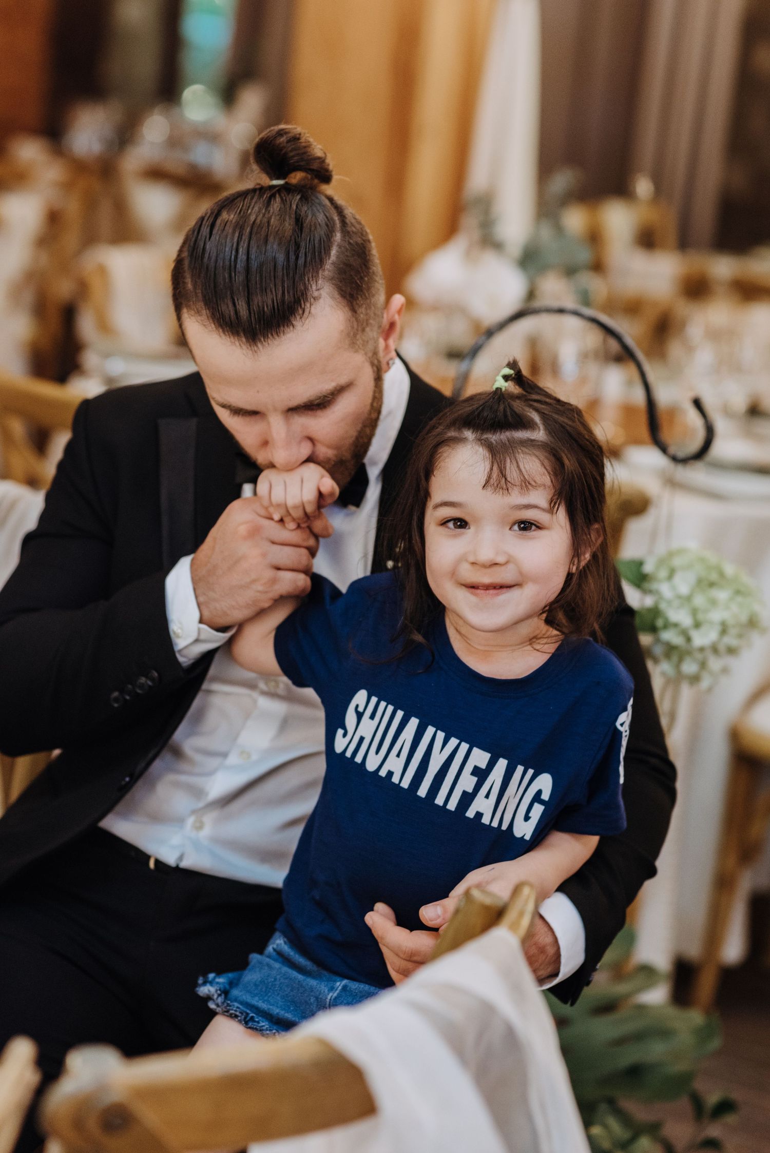 A tender moment between a suited guest and child in casual wear at a wedding reception.