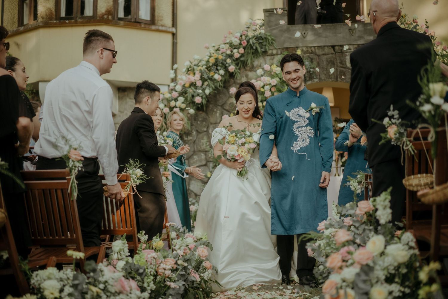 A beautiful wedding ceremony taking place in an elegant church decorated with white and pink floral arrangements.