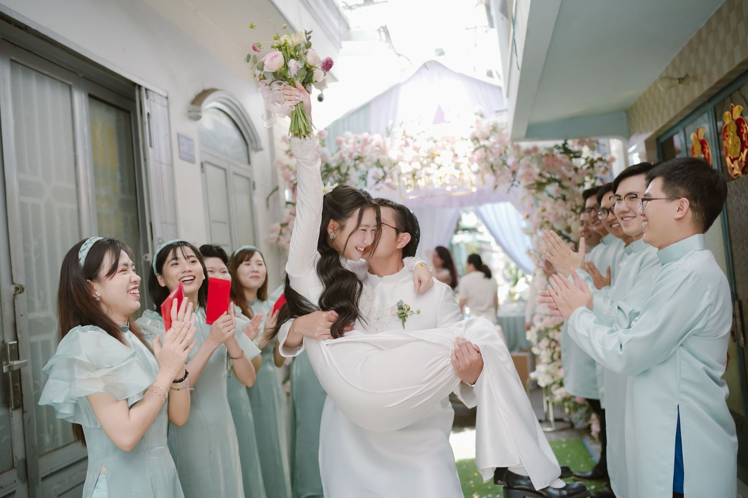 Wedding celebration with guests in mint green attire cheering during a traditional ceremony.