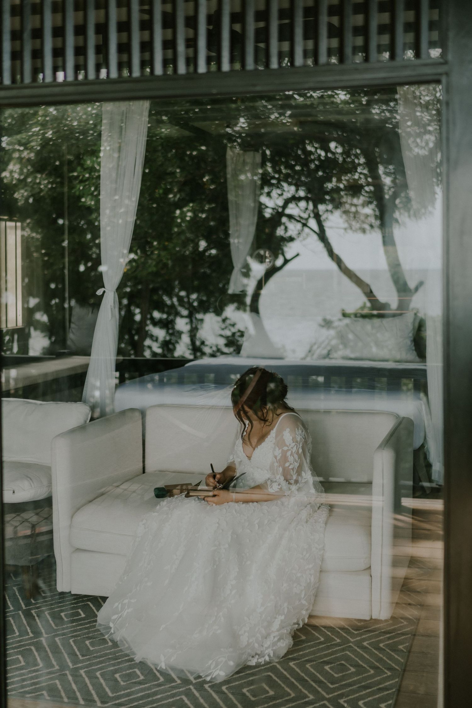 White curtained pavilion overlooks scenic view with someone writing in elegant attire.