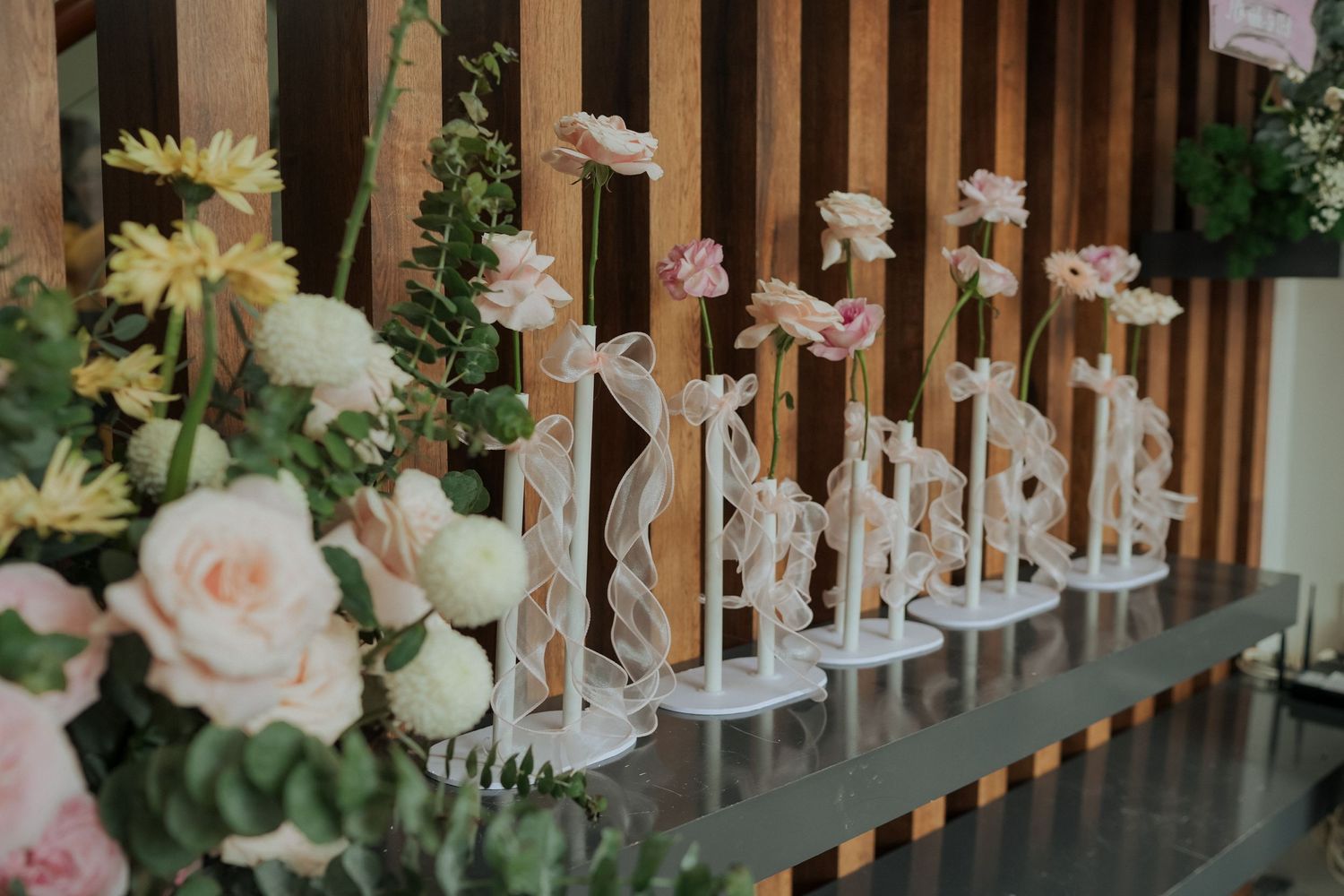Row of elegant crystal trophies displayed on shelf with pink roses and greenery.