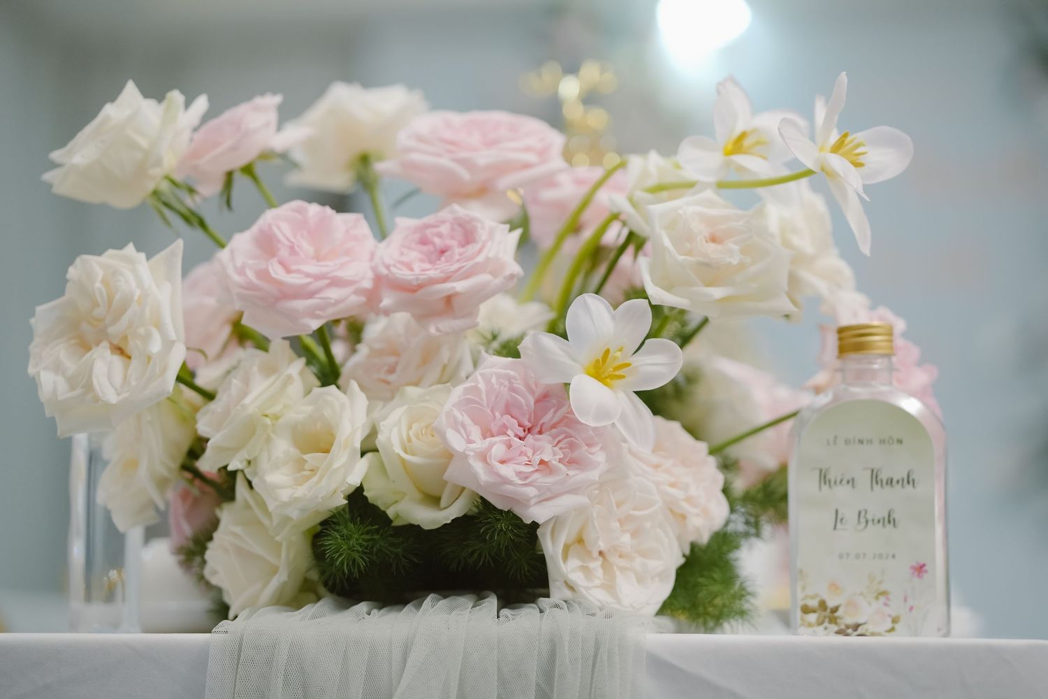 An elegant floral arrangement of pink and white roses with a decorative bottle.