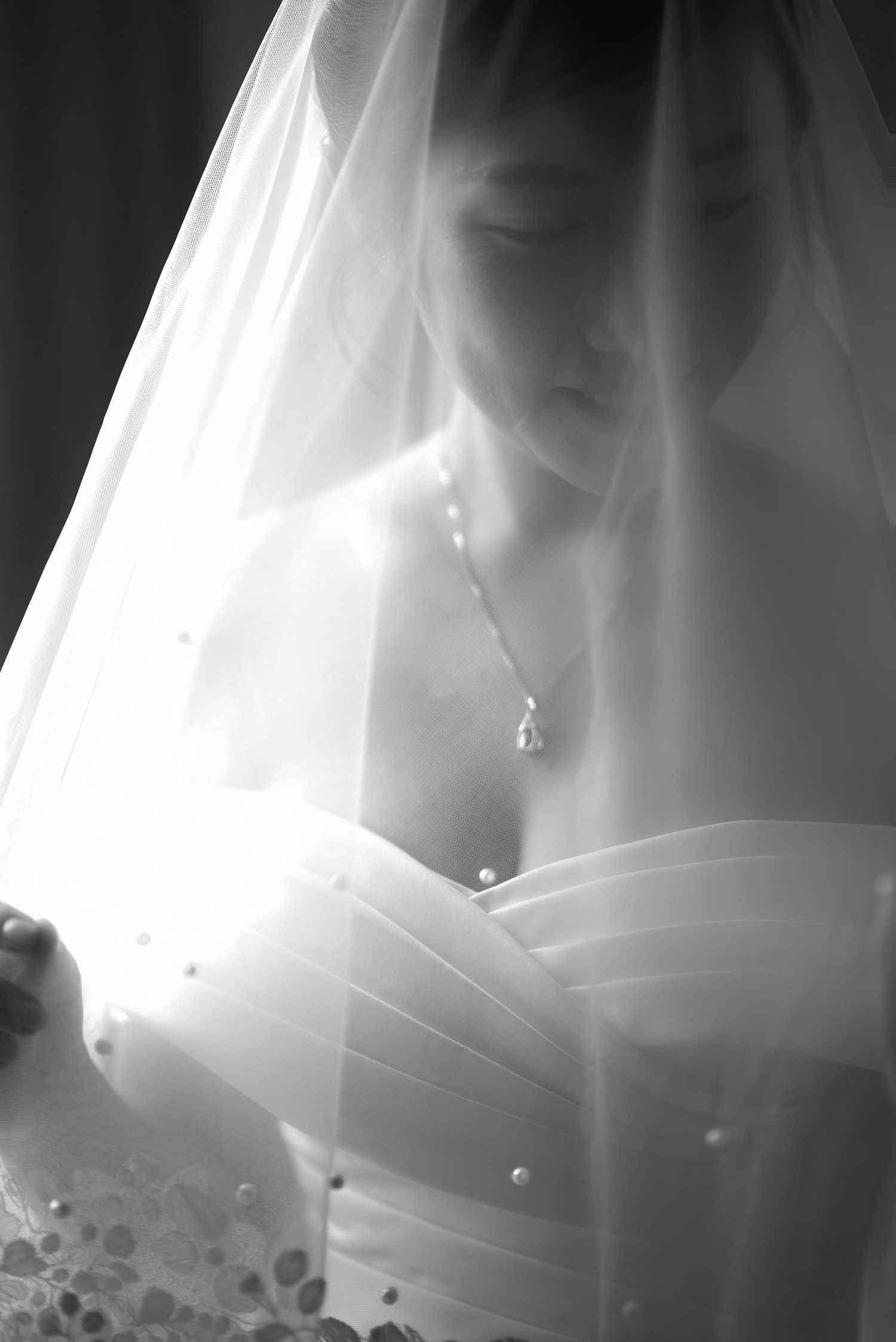 Ethereal black and white portrait of bride in veil with delicate jewelry.