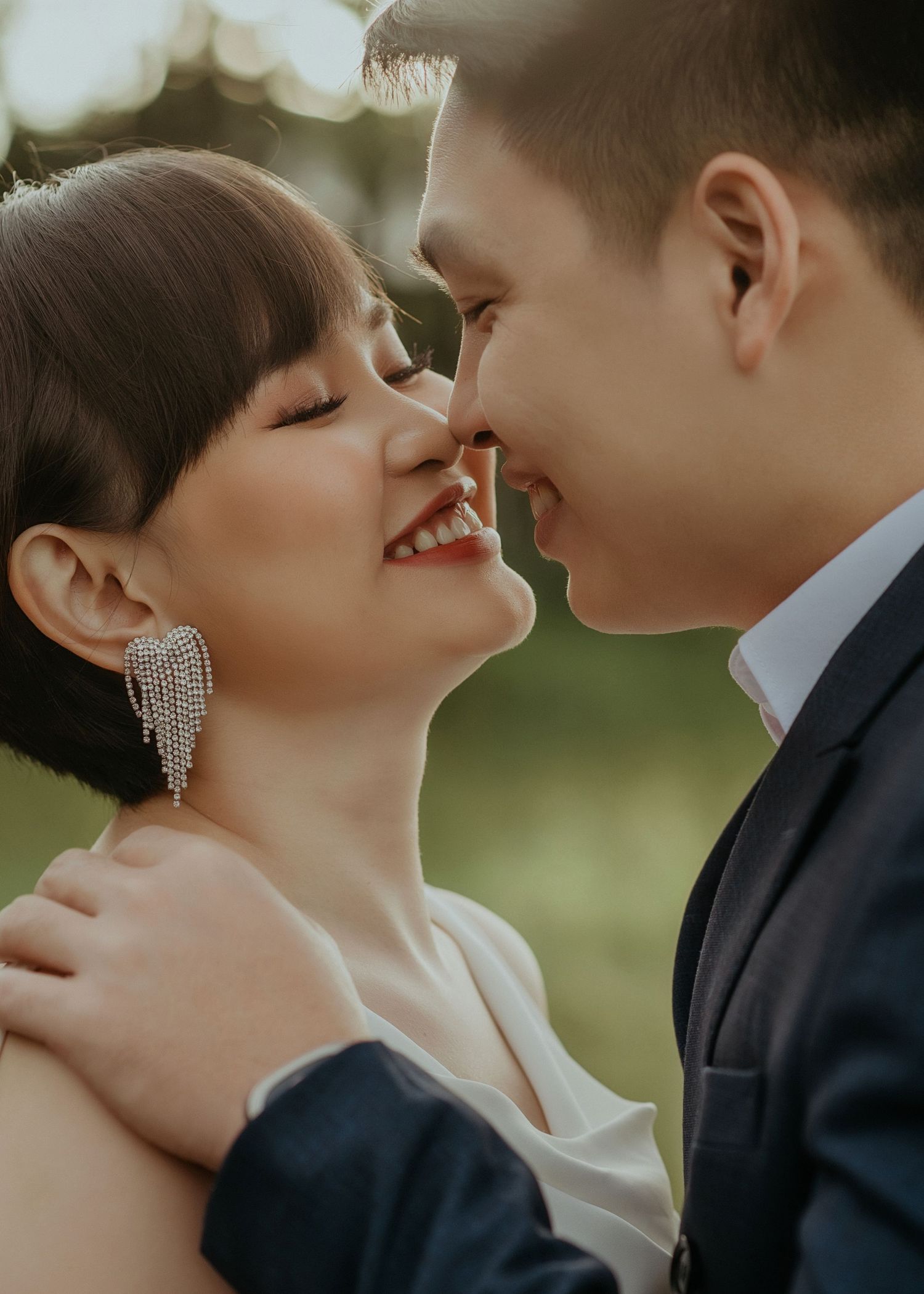 Romantic couple in wedding attire share an intimate moment with sparkling light bokeh in the background.