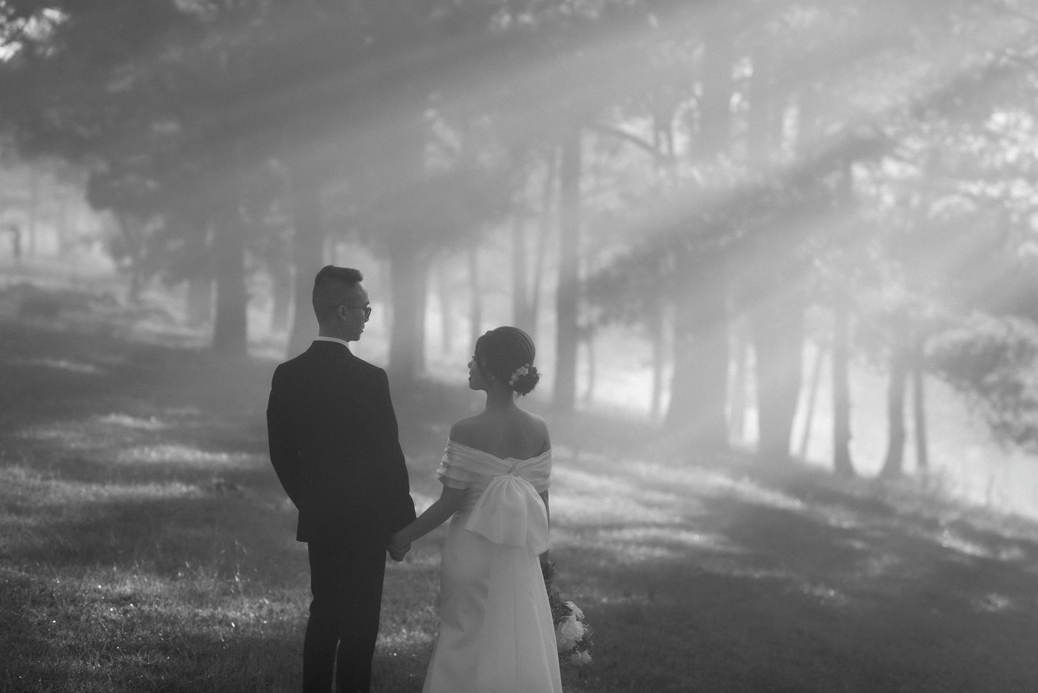 A black and white misty forest scene with a couple silhouetted on their wedding day.