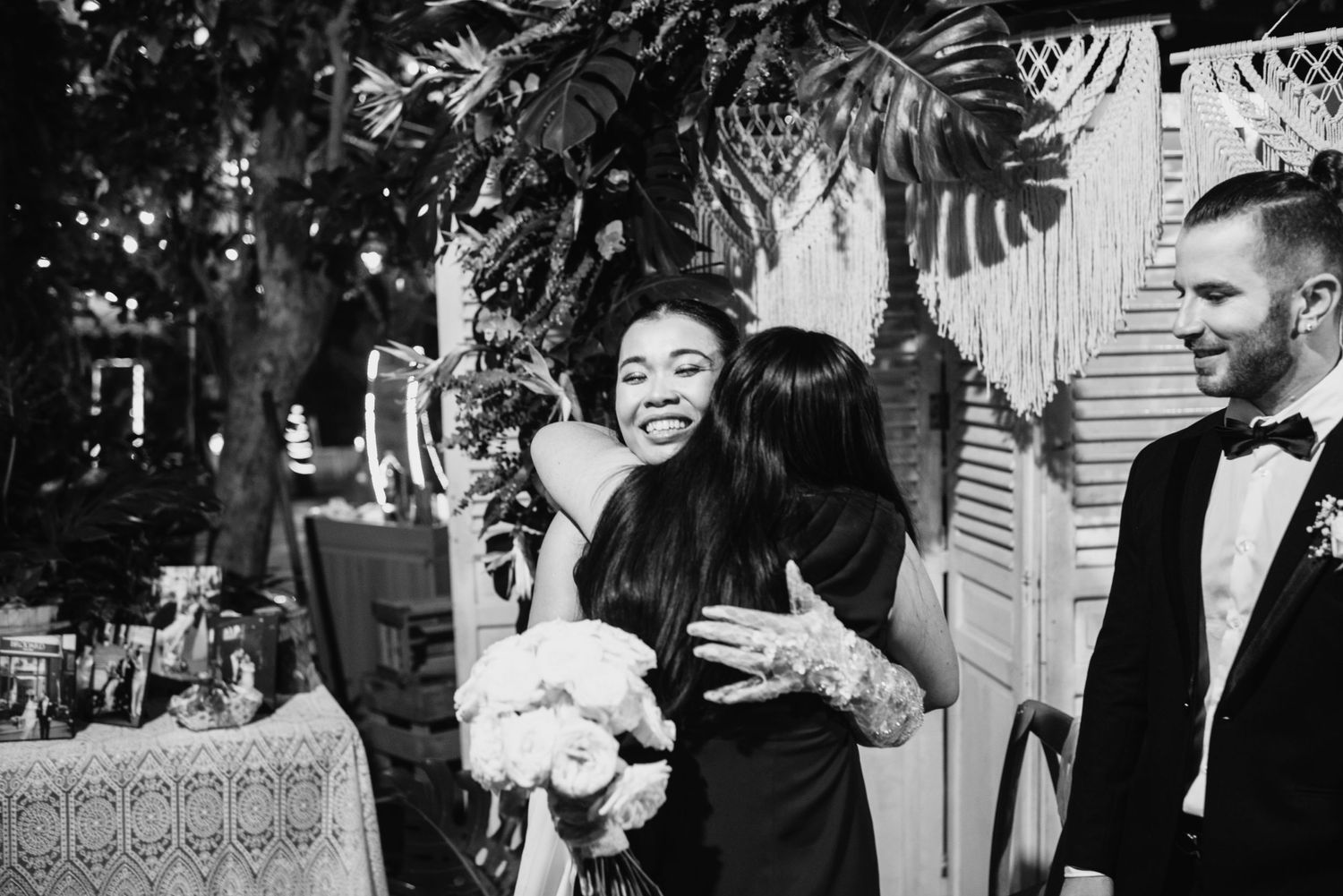 Wedding guests laugh and celebrate during a joyous reception moment in black and white.