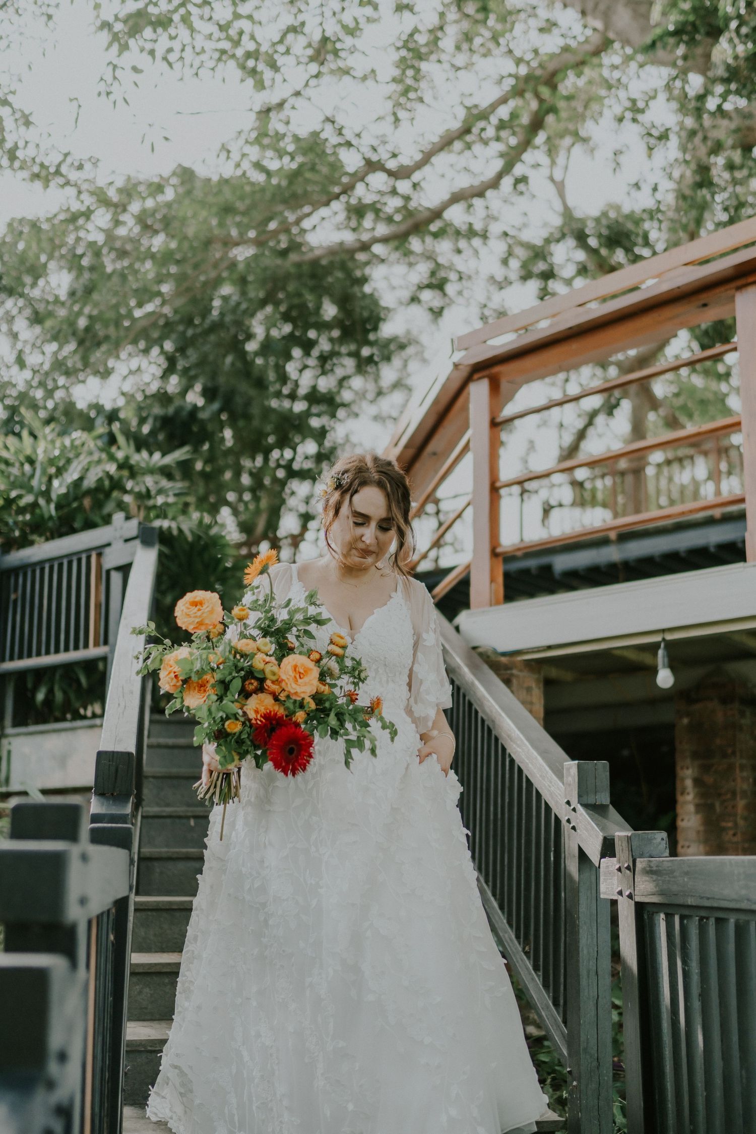 Elegant wedding scene on outdoor staircase with colorful floral bouquet.