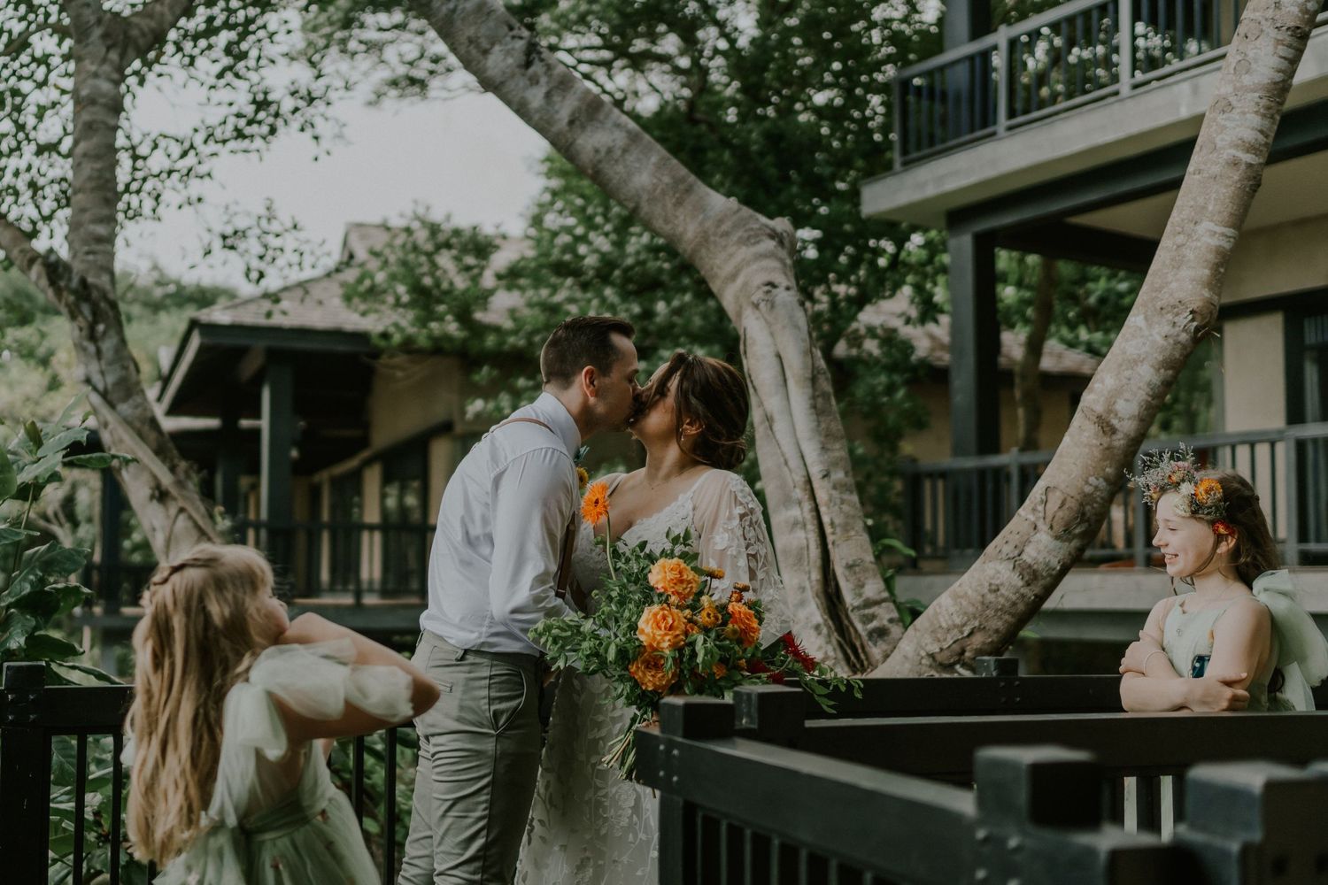 A tender wedding moment shared on a wooden deck surrounded by birch trees and natural greenery.
