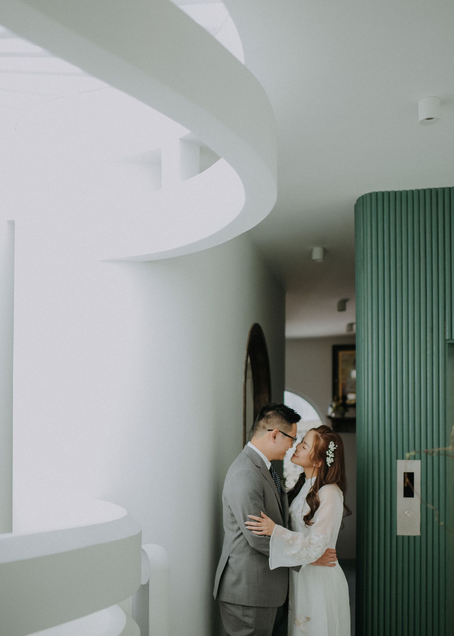 Intimate wedding portrait in a modern interior with curved white walls and green paneling.