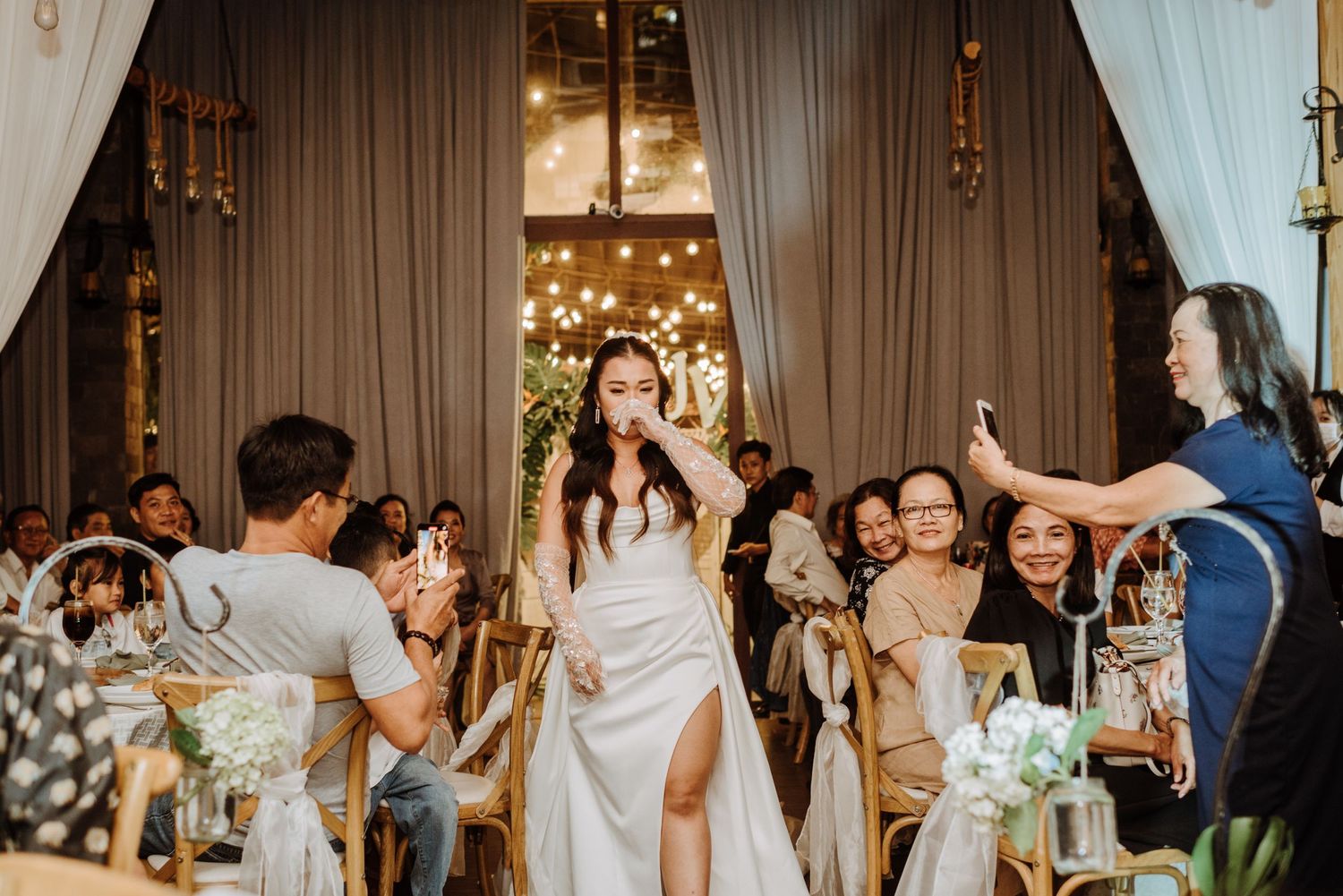 Wedding reception scene with guests taking photos and celebrating.