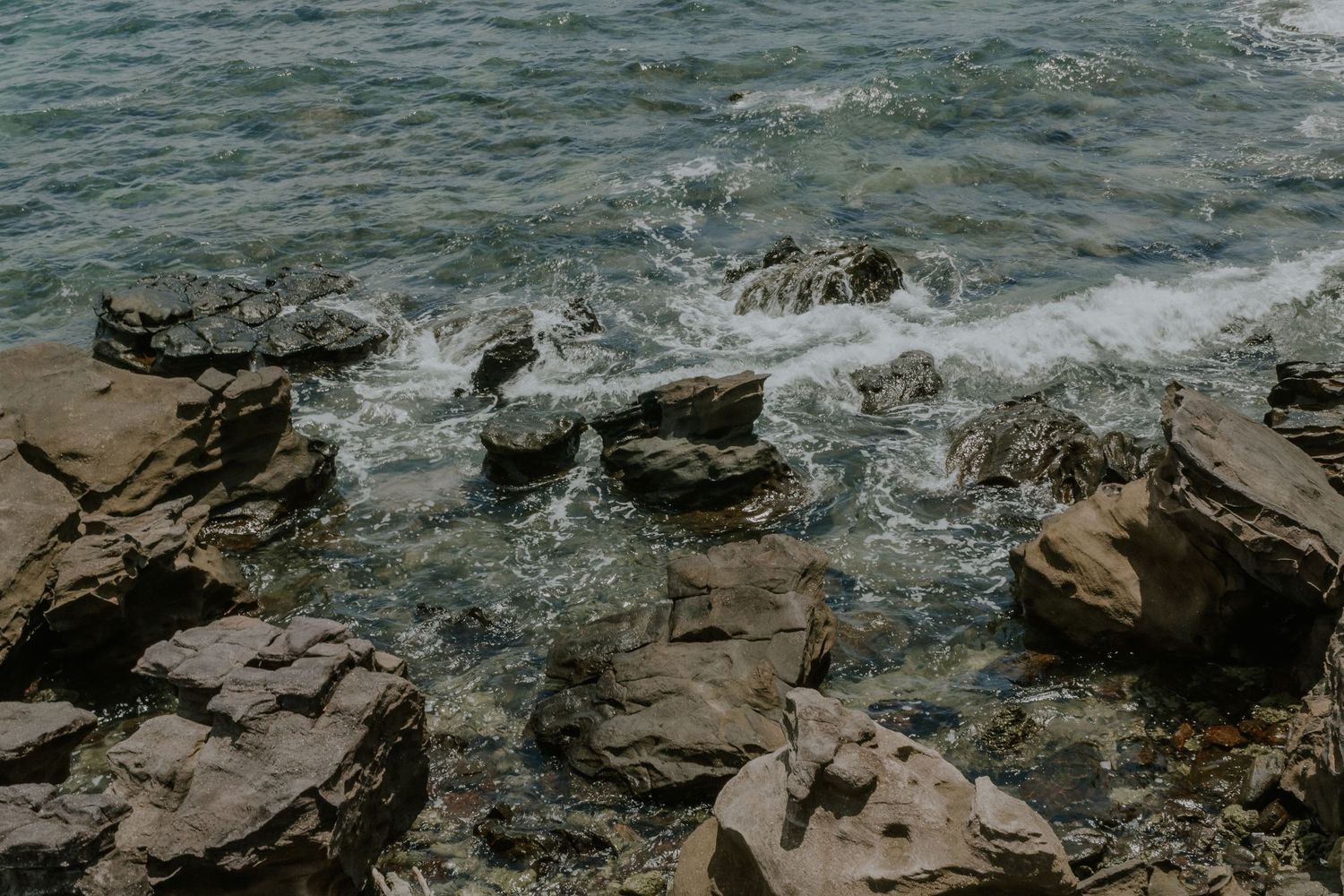 Waves crashing against rocky coastal formations with dramatic water spray.