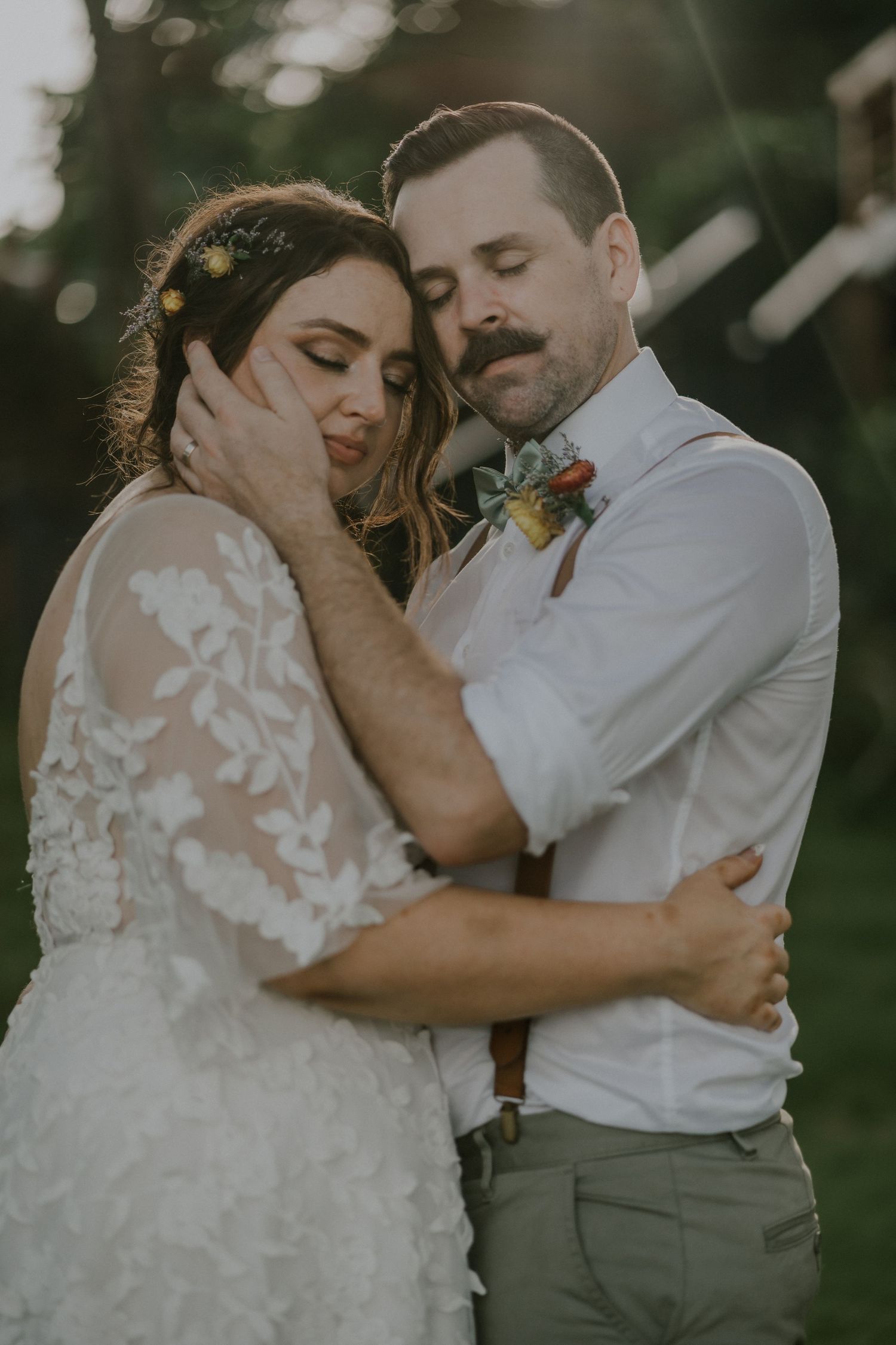 Romantic outdoor portrait of newlyweds sharing tender moment in natural lighting.