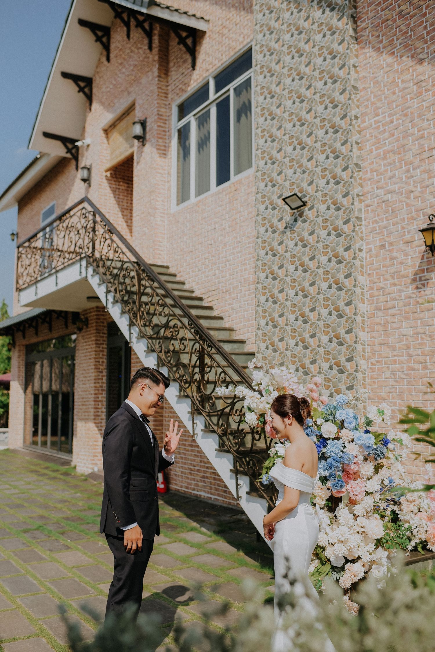 Couple exchanges vows on a brick staircase adorned with cascading blue and white flowers.