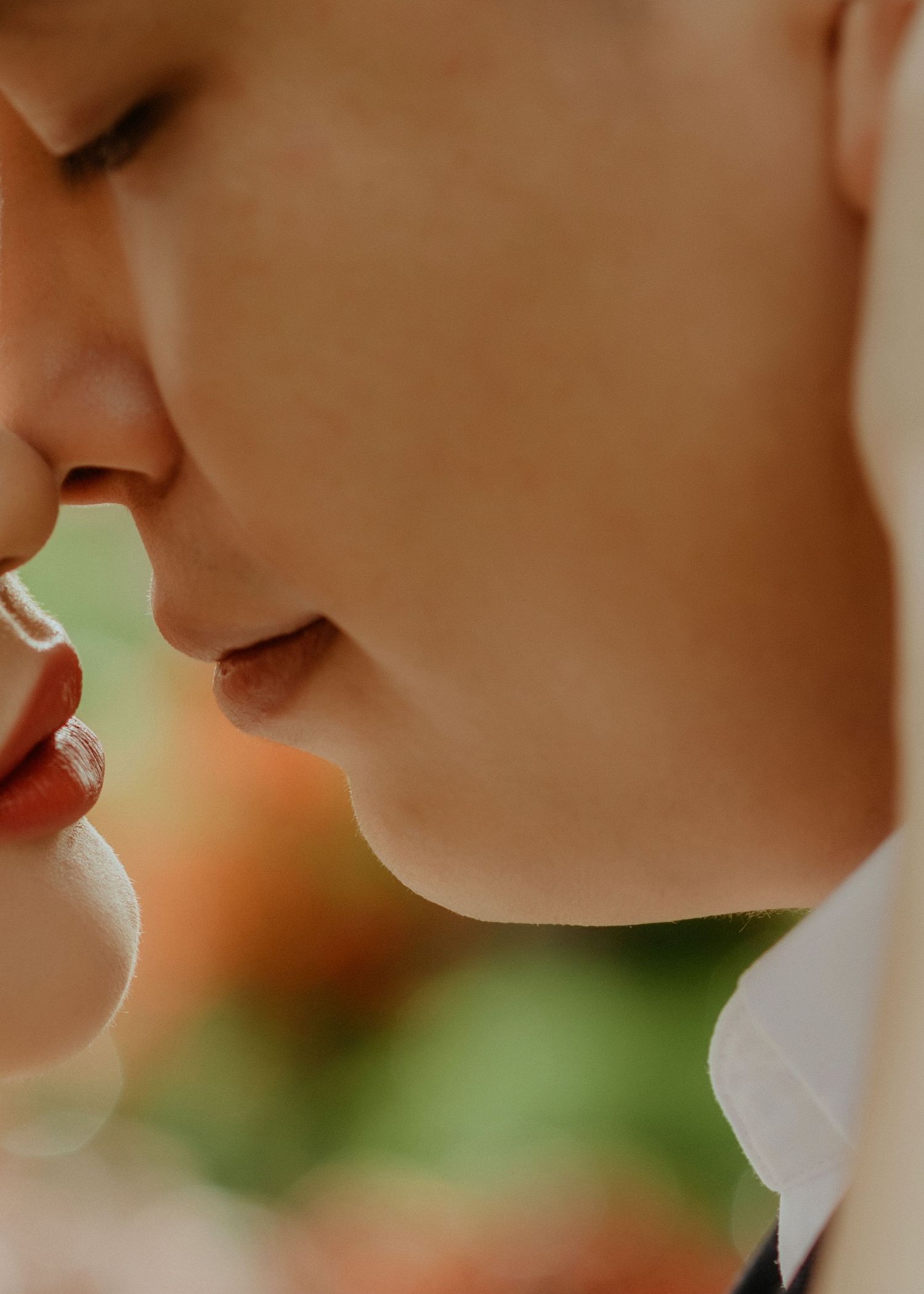 Two people in an intimate close-up shot with romantic lighting and a blurred green background.