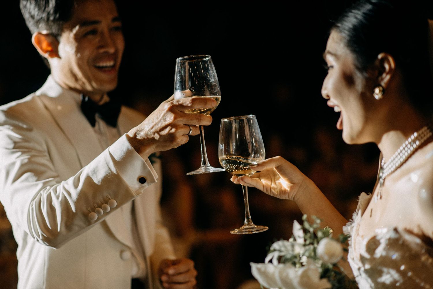 Couple in formal attire toasting with wine glasses at nighttime celebration.