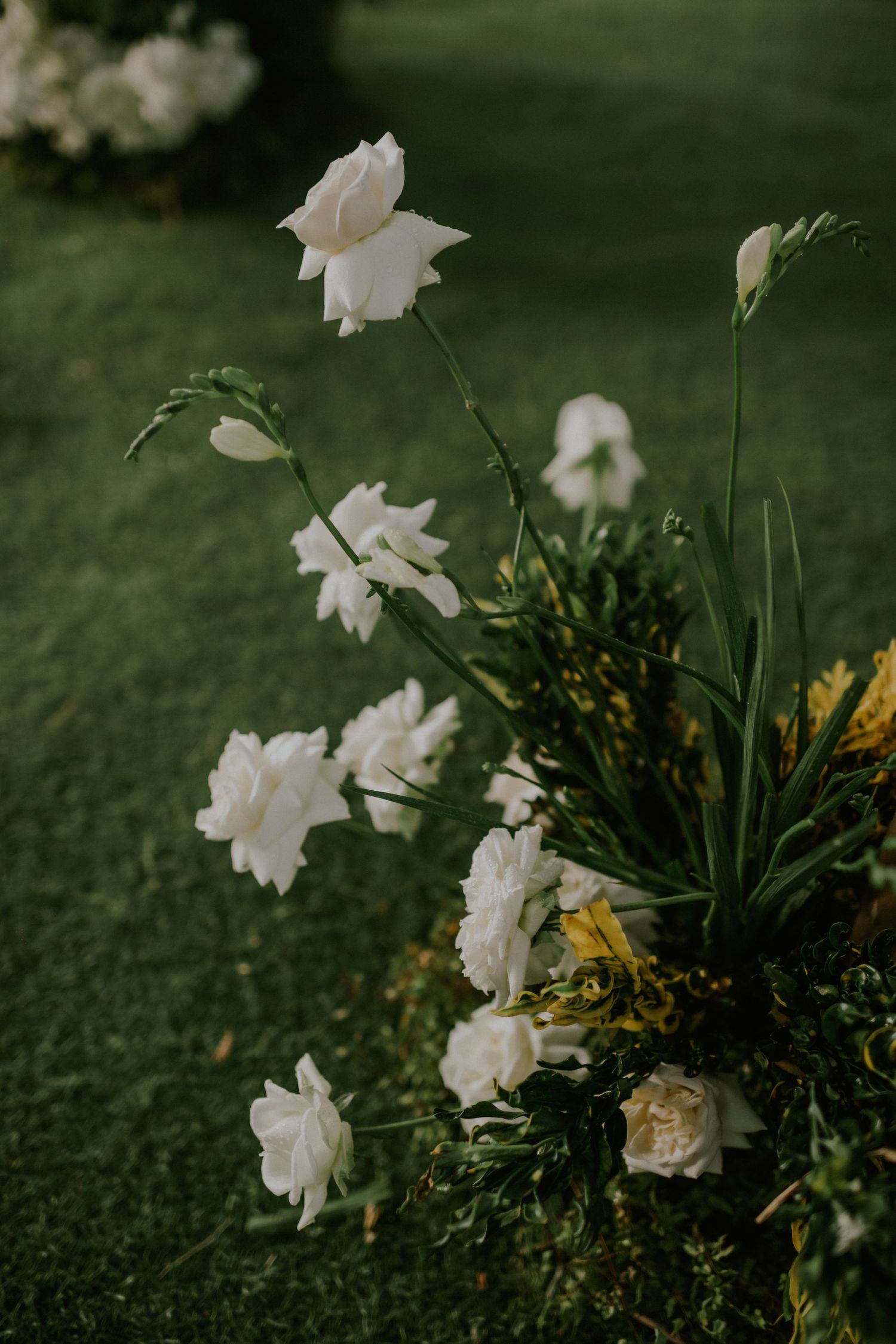 White roses and delicate floral arrangements against a green grass background.