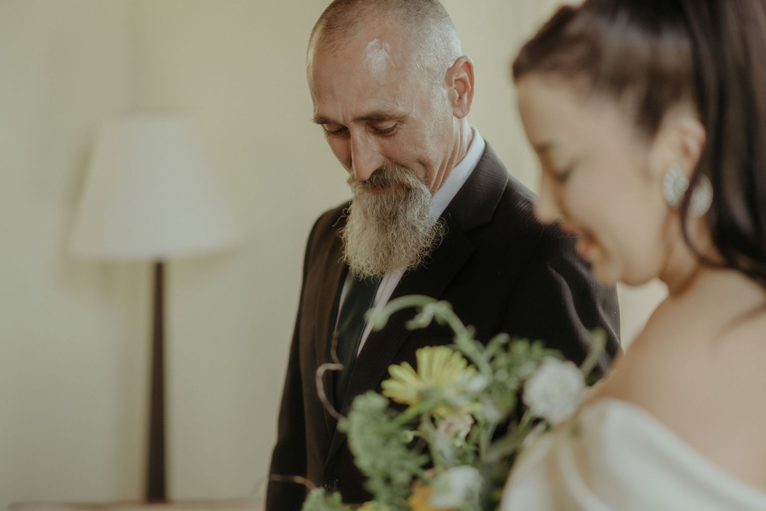 A heartfelt moment between two people during a wedding ceremony with a bouquet of white flowers.