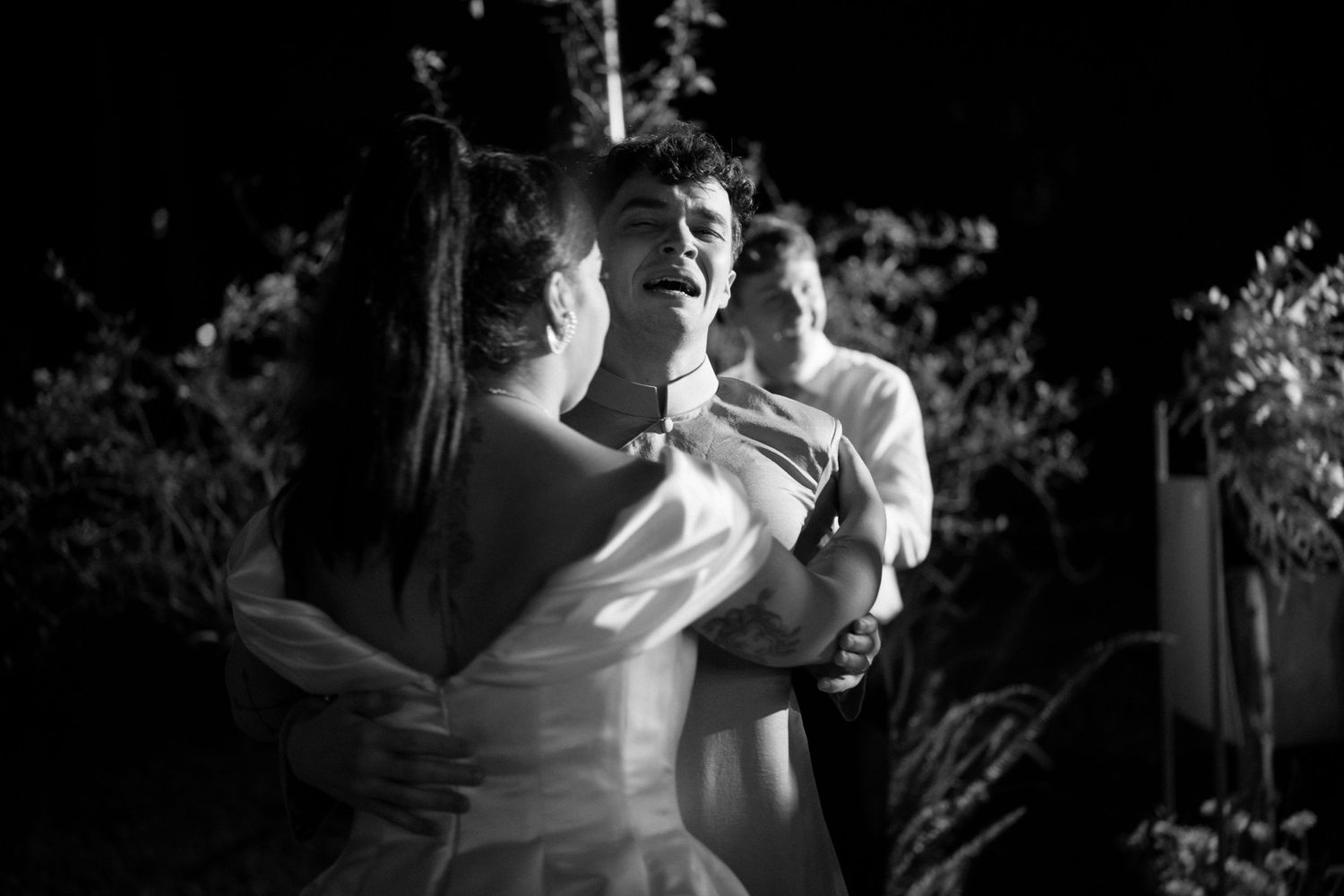 A couple dances together outdoors at night in black and white, with the bride wearing an elegant white dress.