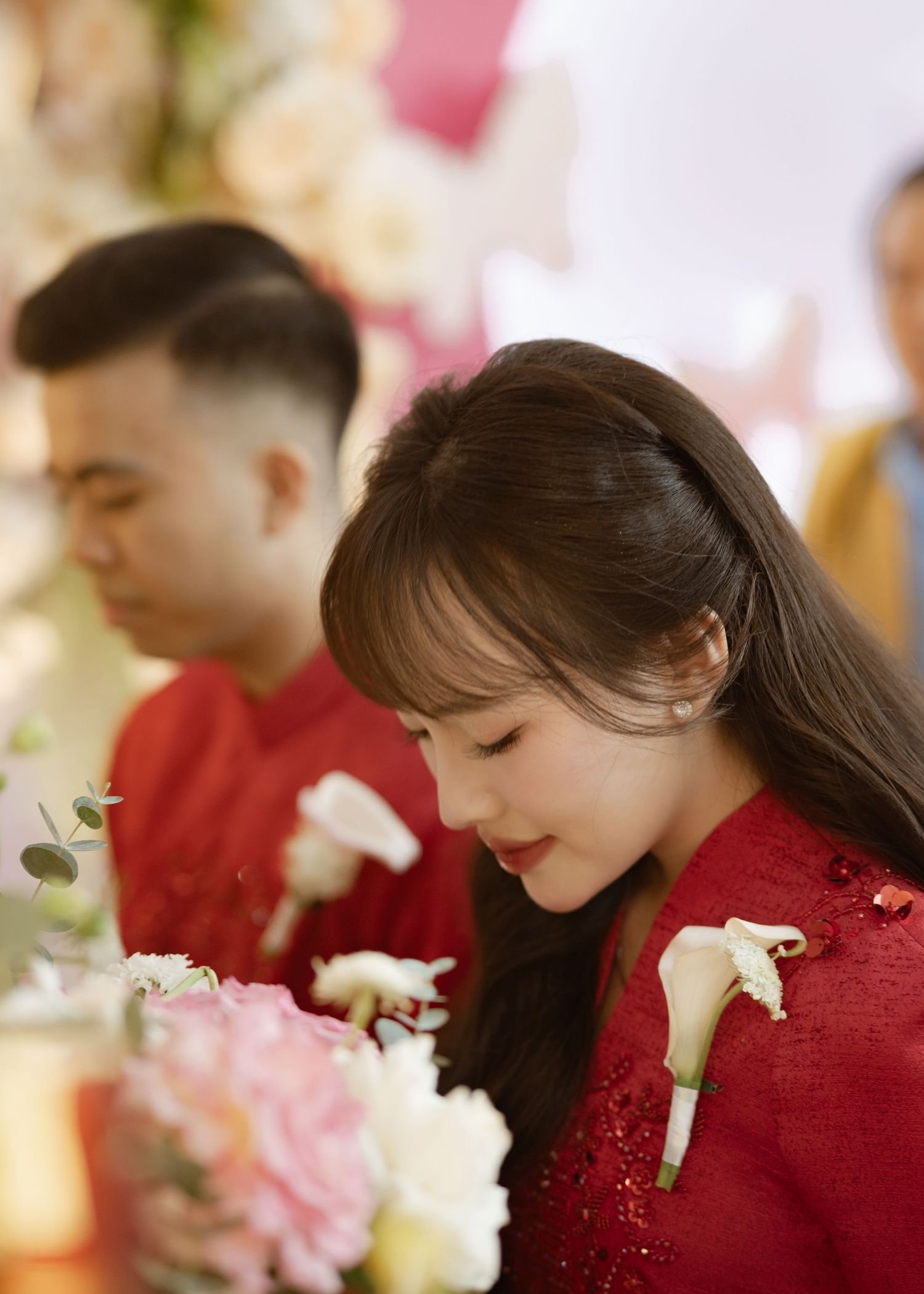 Wedding guests in red attire with white floral boutonnieres at an elegant reception.