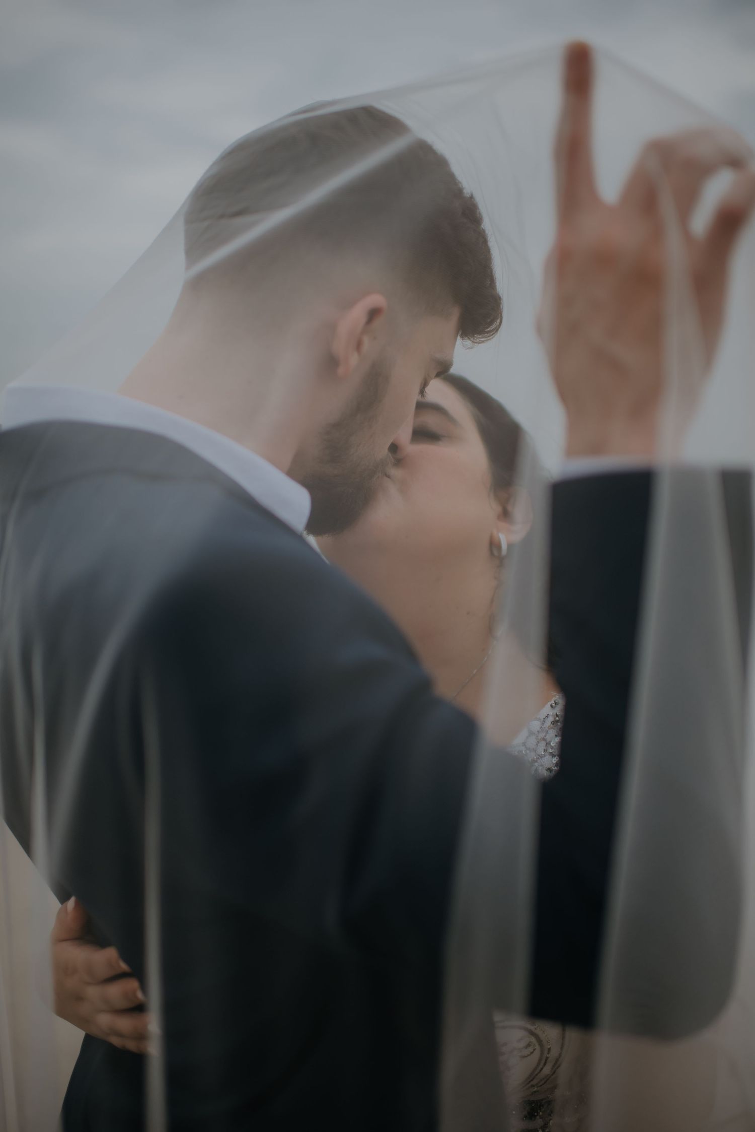 Romantic wedding kiss captured through a flowing veil.