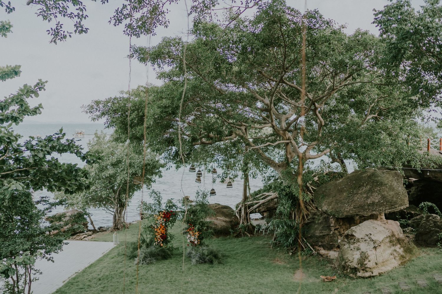 Peaceful garden landscape with tall trees and natural rock formations by the water.