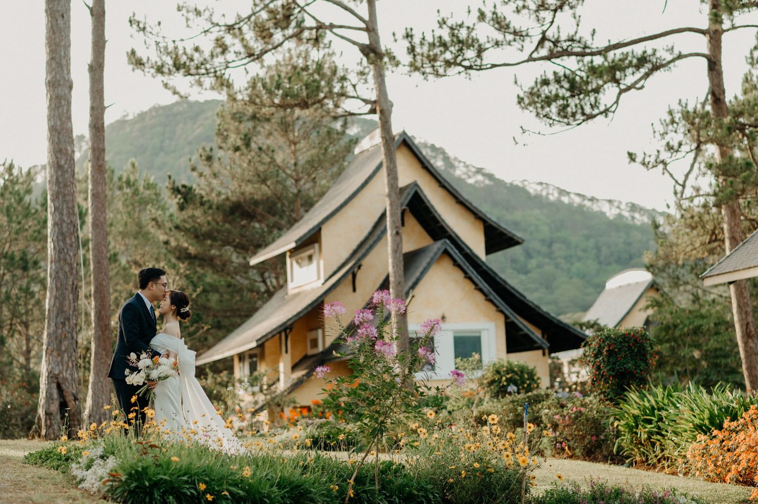 A charming A-frame cabin nestled in a mountain forest with a garden full of blooming flowers.
